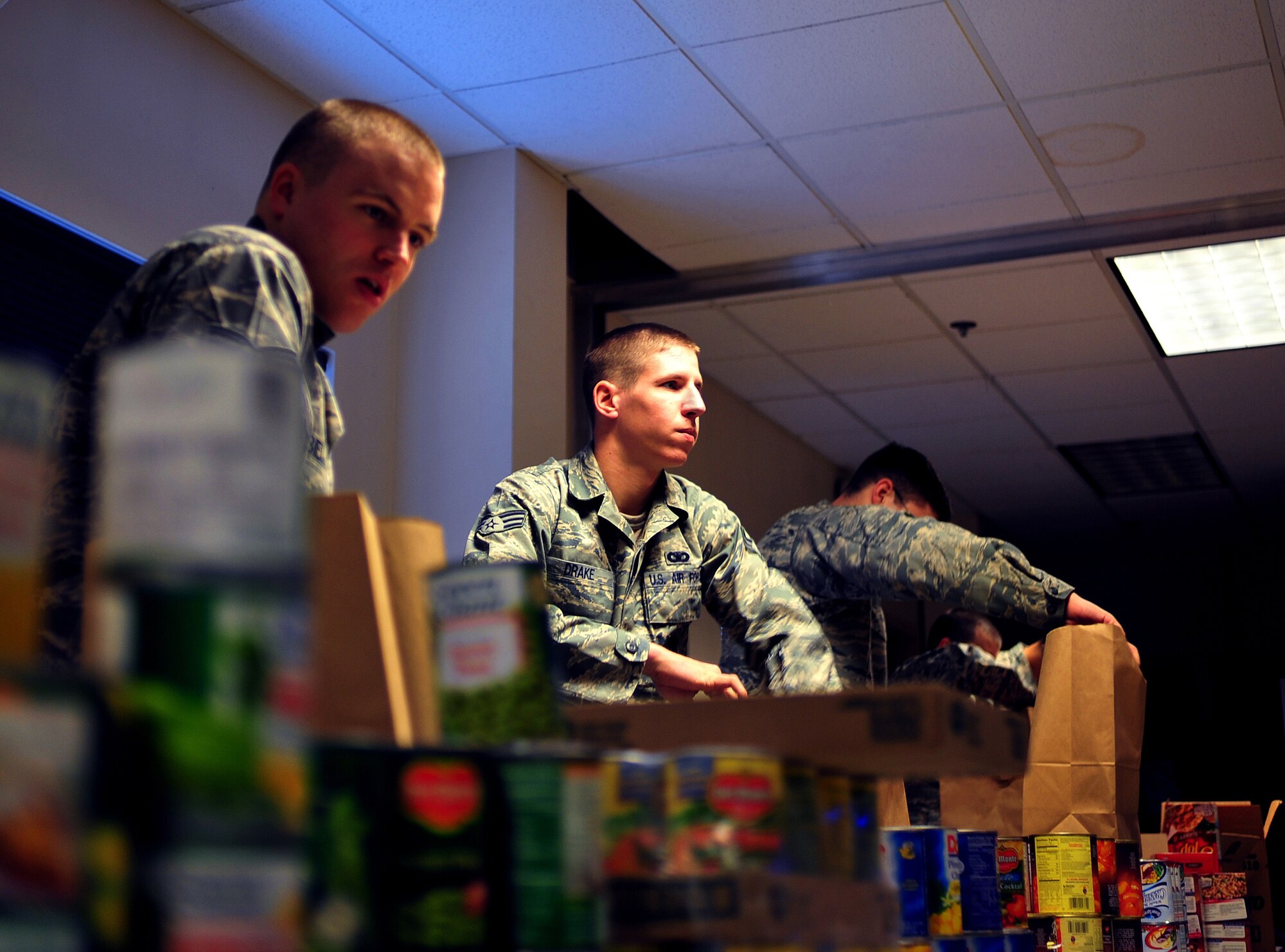 Senior Airman Philip Drake, 354th AMXS, fills a bag with food Nov. 21 at the 354th Civil Engineering "Prime Beef" Building. Airman Drake is part of Airman Leadership School. They took part in Operation: Warm Heart which is a volunteer activity that provides food for needing families during the holiday season. (U.S. Air Force photo by Airman 1st Class Willard E. Grande II)