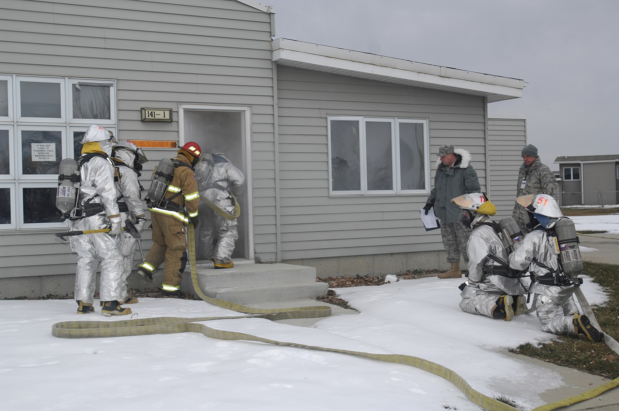 MINOT AIR FORCE BASE, N.D. -- 5th Civil Engineer Squadron firefighters charge into a smoke-filled house as evaluators and fellow firefighters look on during a major accident response exercise (MARE) here Nov. 18. The MARE is used to test the response capabilities of the base’s emergency response teams during inclement weather conditions. (U.S. Air Force photo by Airman 1st Class Jesse Lopez)