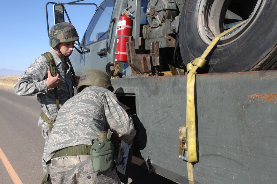 Senior Airman Israel Muniz and Airman Travis Ogburn, both from the 49th Logistics Readiness Squadron, gather equipment from their vehicle to perform a "hasty recovery" on a tracker that was damaged by a simulated improvised explosive device during a phase II exercise at Holloman Air Force Base, N.M., Nov. 20. (U.S. Air Force photo/Airman Sondra M. Escutia)