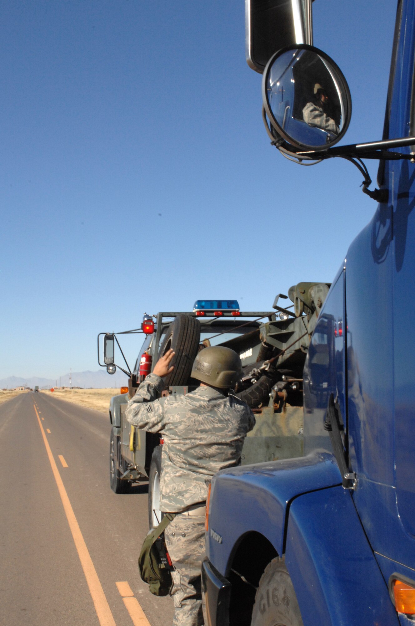 Senior Airman Israel Muniz spots Airman Travis Ogburn, both from the 49th Logistics Readiness Squadron, into position so they can perform a"hasty recovery" on a tracker that was damaged by a simulated improvised explosive device during a phase II exercise at Holloman Air Force Base, N.M., Nov. 20. (U.S. Air Force photo/Airman Sondra M. Escutia)