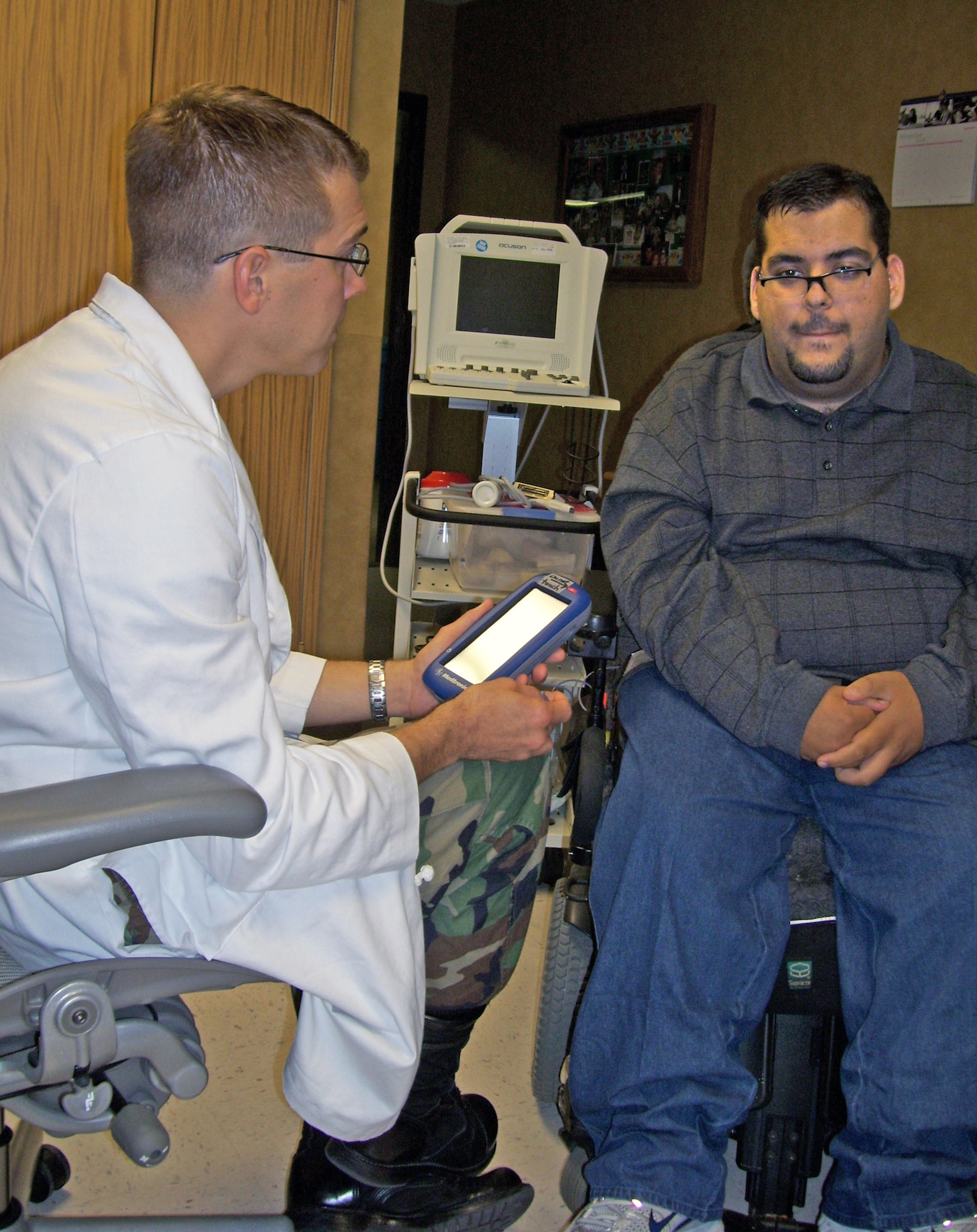 Maj. (Dr.) Brian Faux (left) adjusts the settings on Andy Smith's implanted pump Nov. 12 at the San Antonio Military Medical Complex. The pump was implanted in July 2008 to help control cerebral palsy symptoms and has resulted in increased motor activity. Dr. Faux, a pediatric neurologist, makes slow, subtle adjustments to his levels every week and it usually takes about six months to a year to get patients to the right levels. (U.S. Air Force photo/Sue Campbell) 
