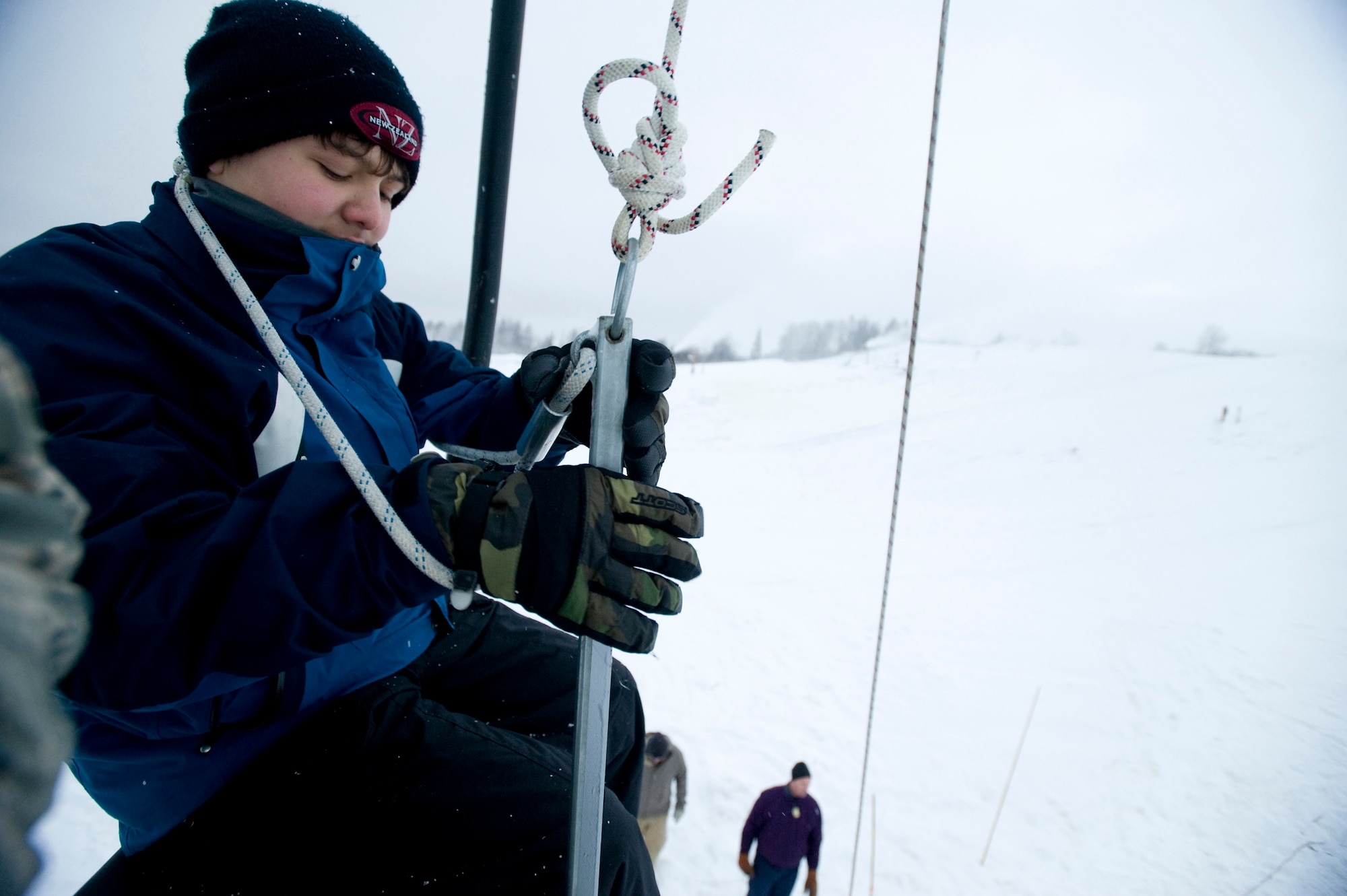 ELMENDORF AIR FORCE BASE, Alaska -- Keoni Appel, a volunteer for the junior ski patrol at Hillberg ski hill, places the safety rope around his body prior to be lowered from the ski lift Nov. 23. The ski patrols performed training on ski-lift evacuation prior to Hillberg's opening this week. (U.S. Air Force photo/Senior Airman Jonathan Steffen)