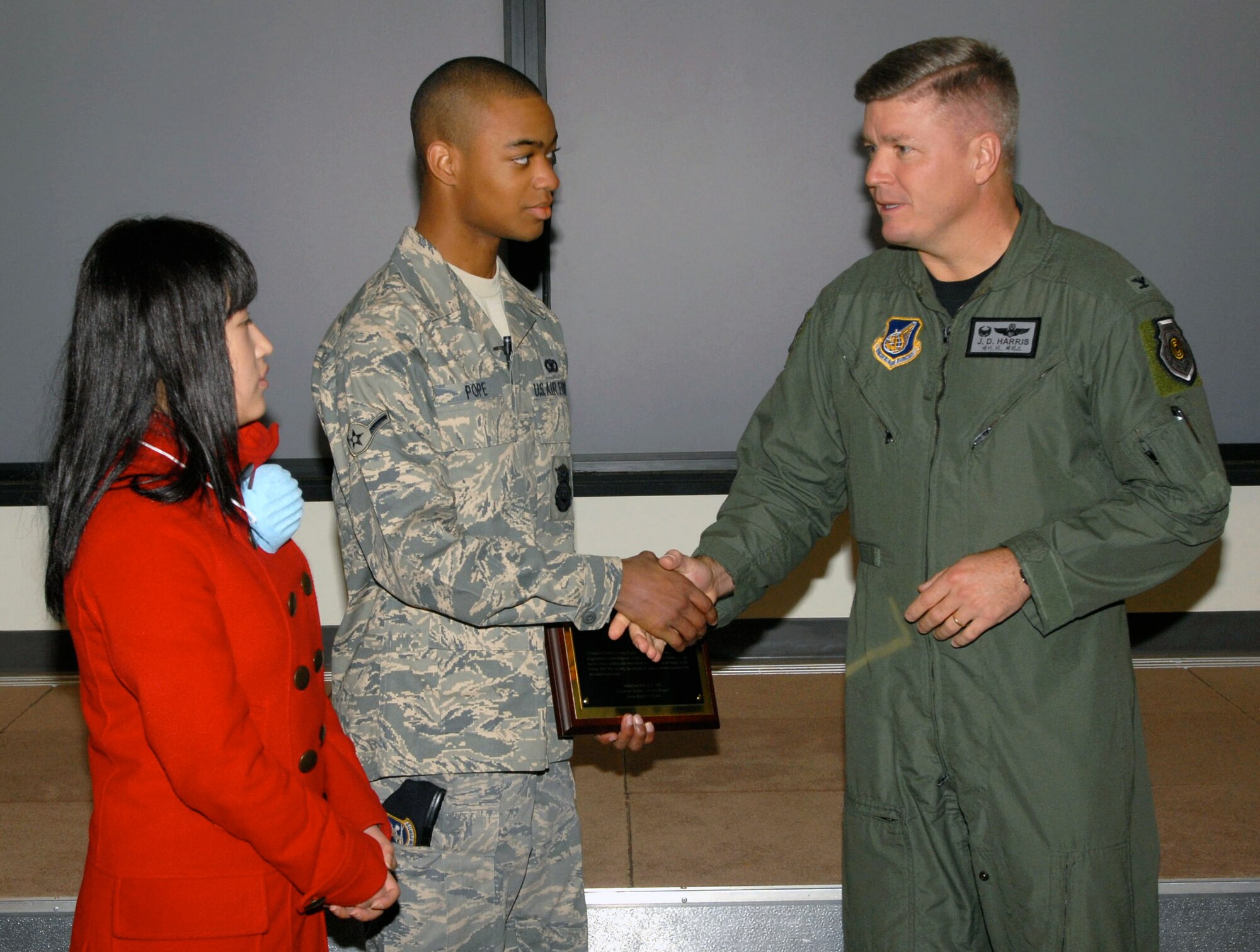 Colonel J.D. Harris presents his commander's coins to Airman Tamarias Pope and You Jin Pak during her Nov. 21 visit to Kunsan Air Base, South Korea. Airman Pope of the 8th Security Forces Squadron donated AB negative blood, which is rare among the South Korean population and specifically for Ms. Pak. The blood he donated ultimately saved her life. Colonel Harris is the 8th Fighter Wing commander. (U.S. Air Force photo/Senior Airman Gustavo Gonzalez) 
