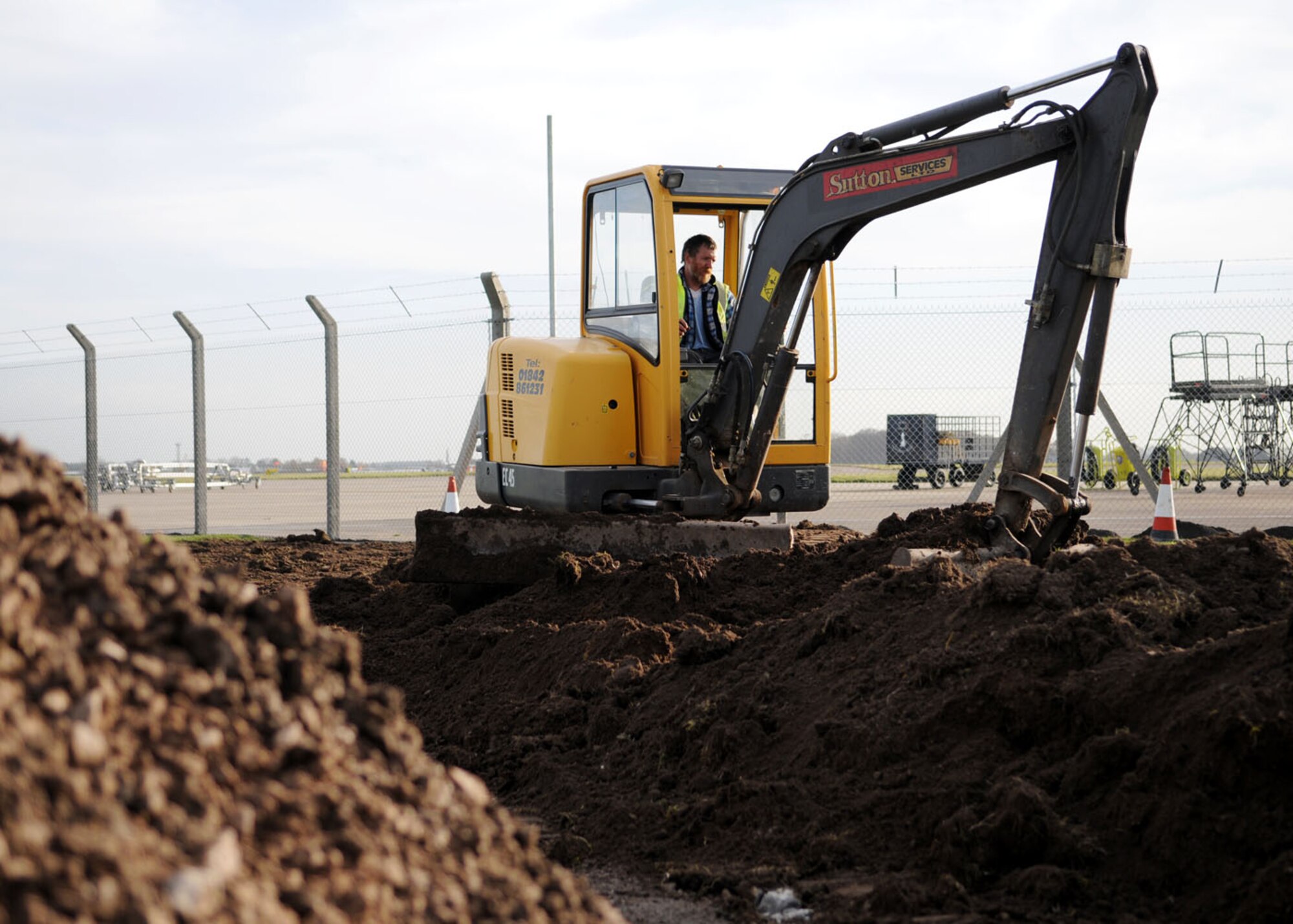 Robert Saunders, a contracted heavy equipment operator, maneuvers a mini excavator to even out mounds of dirt created by the removal of an access road during a reconstruction project on Perimeter Road Nov. 19, 2008 at RAF Mildenhall, England. The project will provide more room for equipment and provide a running path so runners no longer need to run near the road. (U.S. Air Force photo by Staff Sgt. Jerry Fleshman)