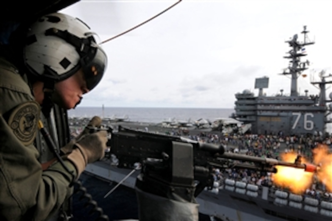 U.S. Navy Petty Officer 2nd Class Keith Holt fires blank rounds from an M-240 machine gun from an SH-60F Seahawk helicopter during an air-power demonstration for the aircraft carrier USS Ronald Reagan in the Pacific Ocean, Nov. 21, 2008. The demonstration was one of many events for more than 1,200 friends and family members of Ronald Reagan Carrier Strike Group sailors.
