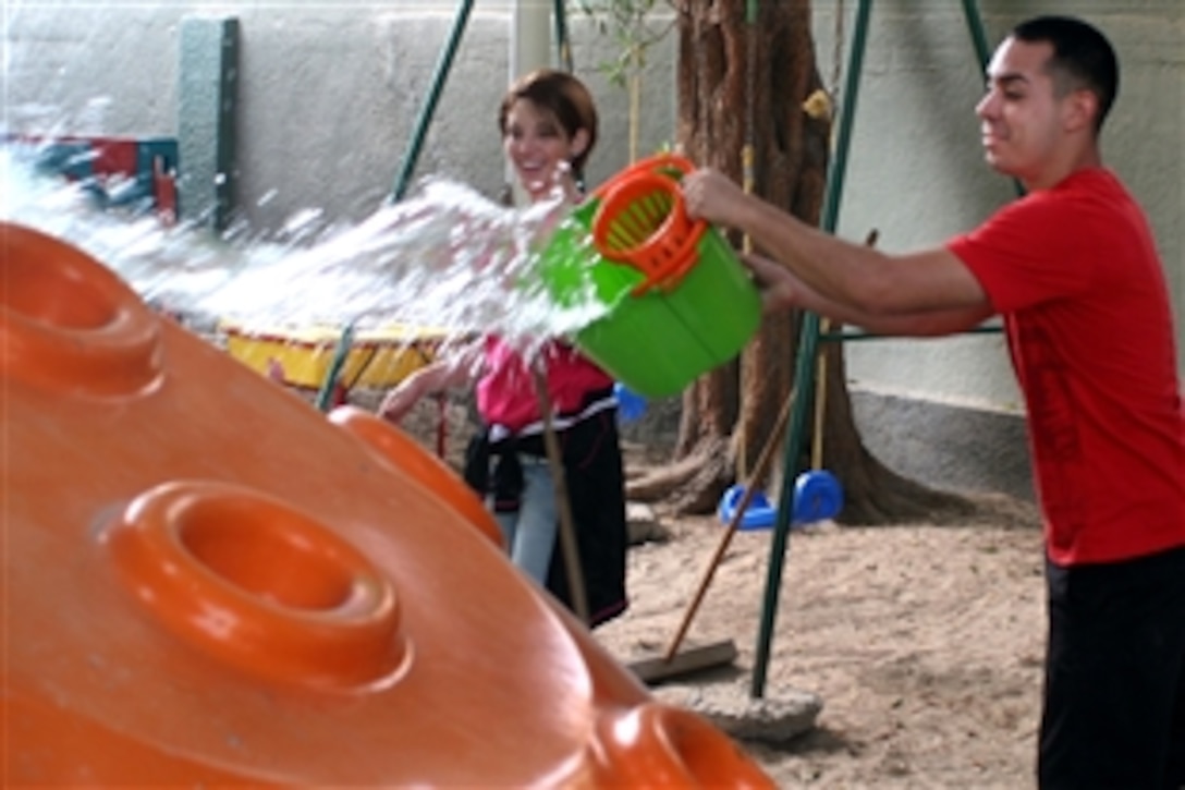 U.S. Marine Corps Cpl. Judy Rivera, left, and Lance Cpl. Oscar Iniguez throw water on a playground slide before cleaning it at the Regional Institute for Active Learning during a community event in Bahrain, Nov. 15, 2008. Rivera and Iniguez are assigned to the amphibious transport dock ship USS San Antonio, deployed as part of the Iwo Jima Expeditionary Strike Group supporting maritime security operations in the U.S. 5th Fleet area of responsibility.