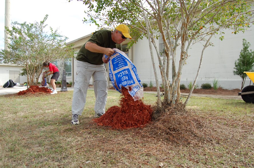 Master Sgt. Tom Haddock (foreground), Top 3 president, and Senior Master Sgt. Laurie Klausutis, install new cypress mulch outside Duke Field's Outpost facility during the organization's recent landscaping project.  A dozen Top 3 members volunteered their time to spruce up the base's appearance there and at the gate along Highway 85.  (Courtesy photo).