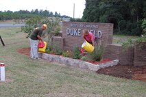 Master Sgt. Tom Haddock (left), Duke Field's Top 3 president, and his wife, Susan, water plants that they and other organization volunteers had just installed in front of the base's main entrance sign recently. A dozen Top 3 members volunteered their time to spruce up the base's appearance there and at the Outpost/Club facility.  (Courtesy photo).
