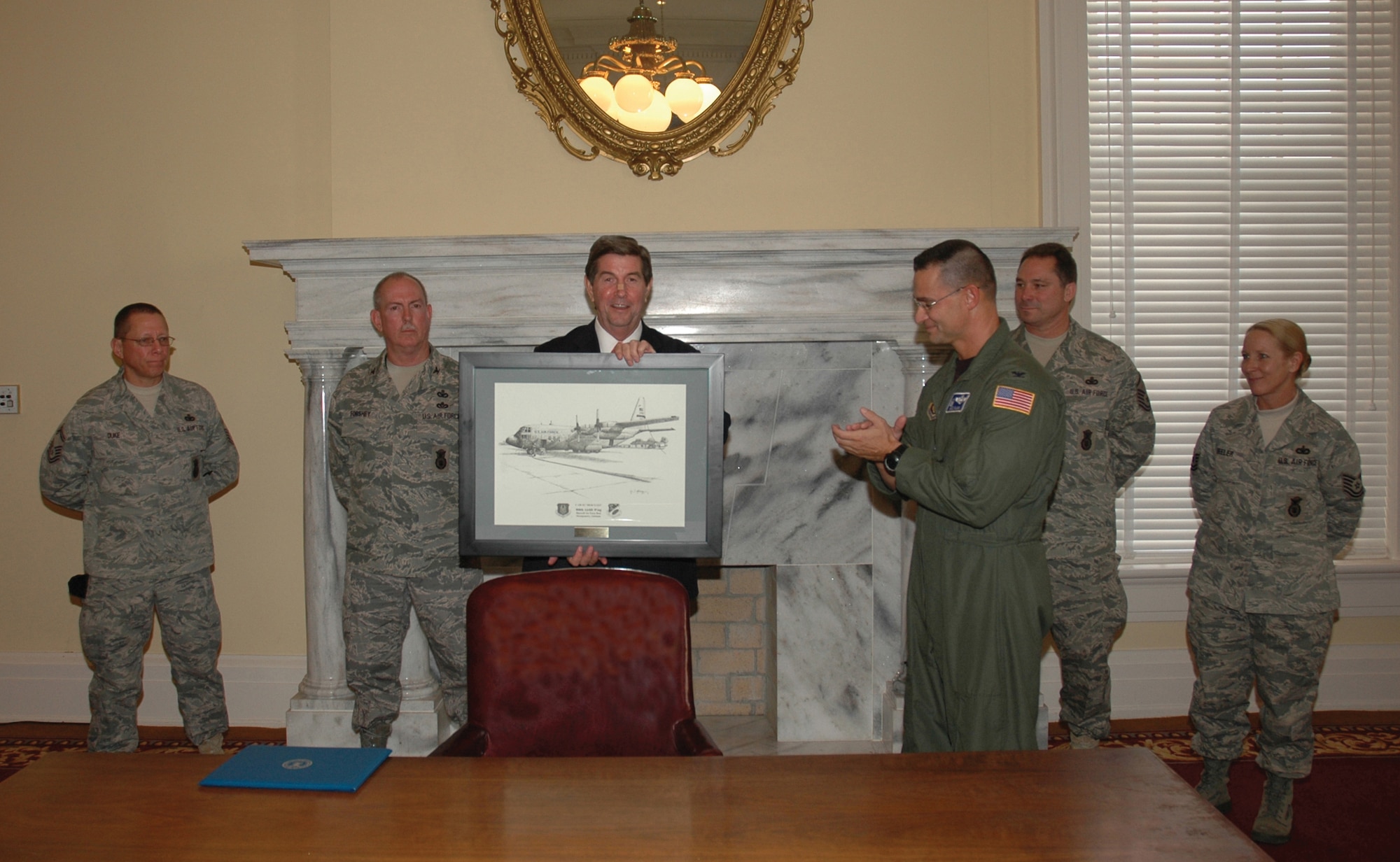 Ala. Gov. Bob Riley, center, displays a limited edition, framed and engraved print of a 908th Airlift Wing C-130 presented to him by 908th AW Commander Col. Brett J. Clark and formerly deployed security forces members Nov. 20.  The 908th AW contingent also presented the governor with a U.S. flag that flew over an observation post staffed by unit security forces members while deployed to Kirkuk, northern Iraq. The reservists were on hand as the governor unveiled a new initiative to provide more help to the state's returning warriors. The remaining members are (from left) Senior Master Sgt. Owen Duke, former 908th Mission Support Group Commander Col. William Forshey, Master Sgt. Tim Oliver and Tech. Sgt Kelly Beeler. (U.S. Air Force Photo by Lt. Col. Jerry Lobb)         
