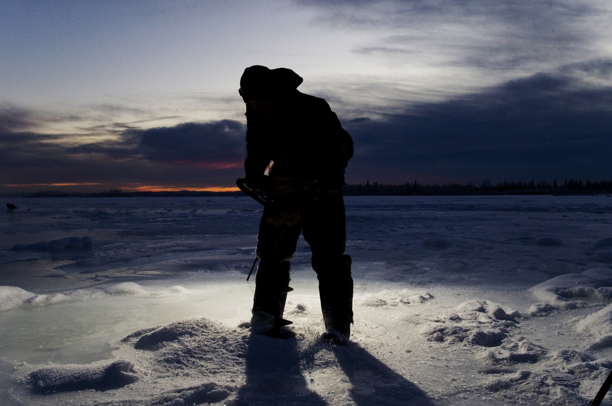Airman 1st Class Caleb Hurley uses an ice auger on the Tanana River Nov. 24, 2008, Fairbanks, Alaska in the first phase to building an ice bridge. Airman Hurley is with the 354th Civil Engineer Squadron. The ice bridge provides the 354th CES members access to perform annual maintenance on Eielson's training and bombing ranges. The process of building the ice bridge takes six to 10 weeks in a sub-arctic enviroment and will later melt back into the river in the summer months. (U.S. Air Force photo/Airman Laura Max)(released) 
