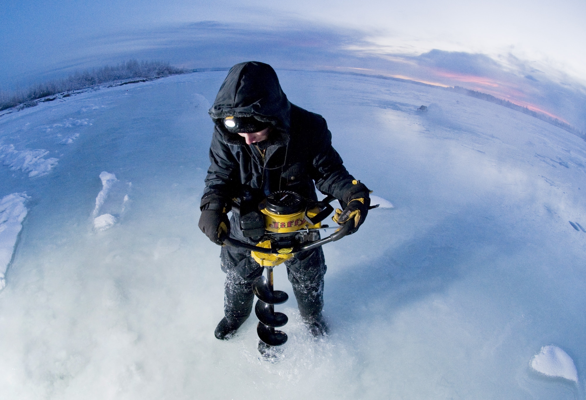 Airman 1st Class Caleb Hurley drills a hole in the Tanana River Nov. 24, 2008, Fairbanks, Alaska in the first phase to building an ice bridge. Airman Hurley is with the 354th Civil Engineer Squadron. The ice bridge provides the 354th CES members access to perform annual maintenance on Eielson's training and bombing ranges. The process of building the ice bridge takes six to 10 weeks and will later melt back into the river in the summer months. (U.S. Air Force photo/Airman Laura Max)(released)
