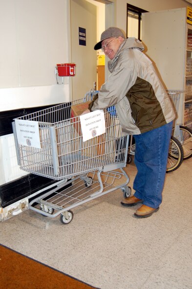Rodney Diseth places a gift box into the donation cart located near the customer service desk at the front of the Commissary. Donated gift boxes will be given to the first sergeants at Malmstrom to distribute to needy Air Force families here. (U.S. Air Force photo/Valerie Mullett)