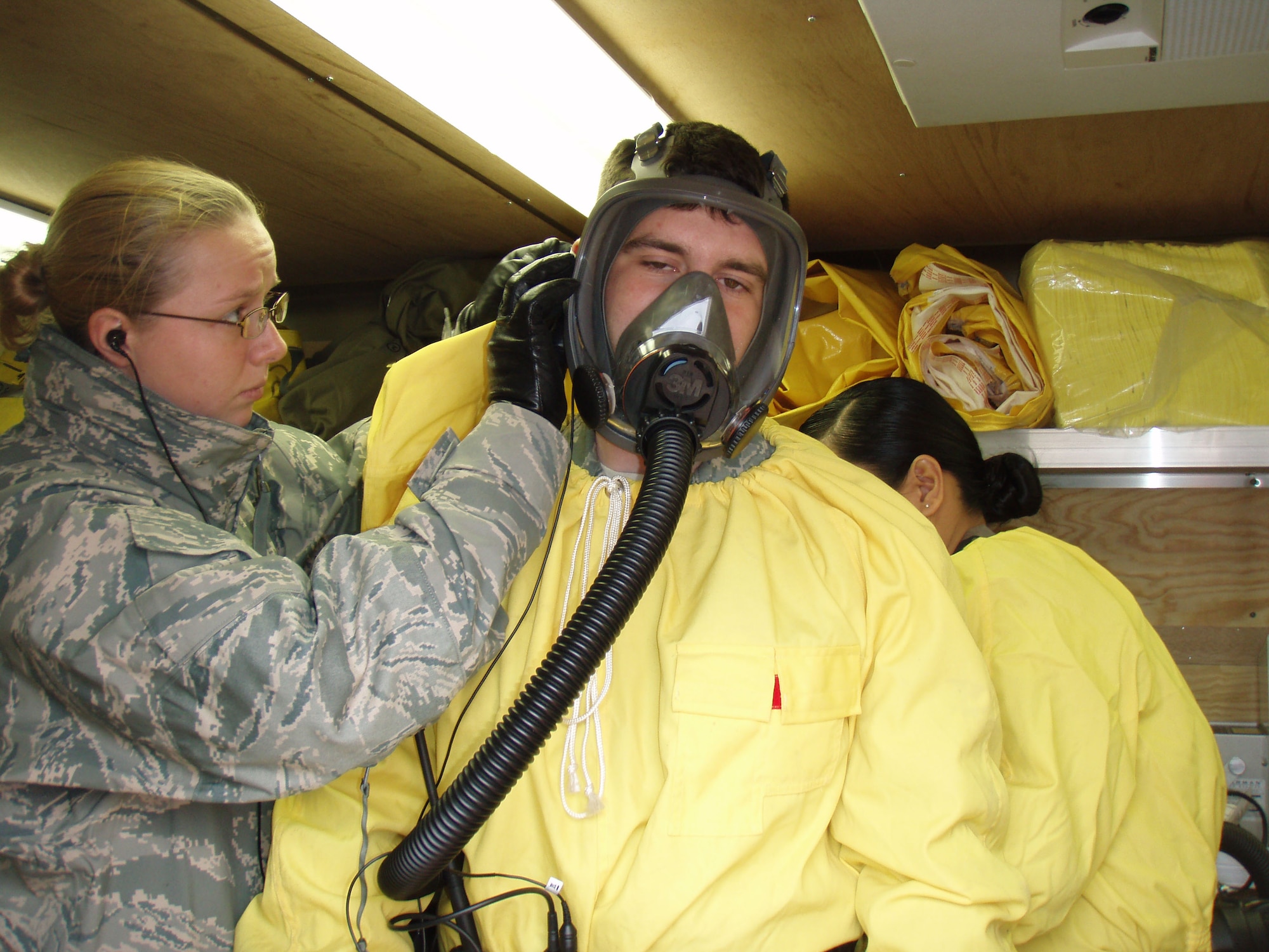 1st Lt. Cyrstal Bown tapes a communications instrument into Airman 1st Class Michael Frank's ear prior to sending him out to test a hazardous material site during an exercise scenario. Both are members of the bioenvironmental team. (U.S. Air Force courtesy photo)
