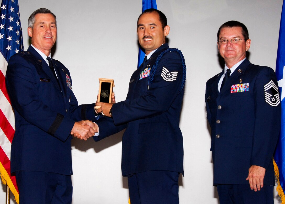 Tech. Sgt. Wesley Garcia, center, of the 82nd Training Group accepts the Junior Military Training Leader of the Quarter award from Brig. Gen. O.G. Mannon, 82nd Training Wing commander, Nov. 20 during the Quarterly Tech Training Awards in the base theater. Also pictured is Chief Master Sgt. Michael Crowley, right, superintendent of the 882nd TRG. (U.S. Air Force photo/Harry Tonemah)