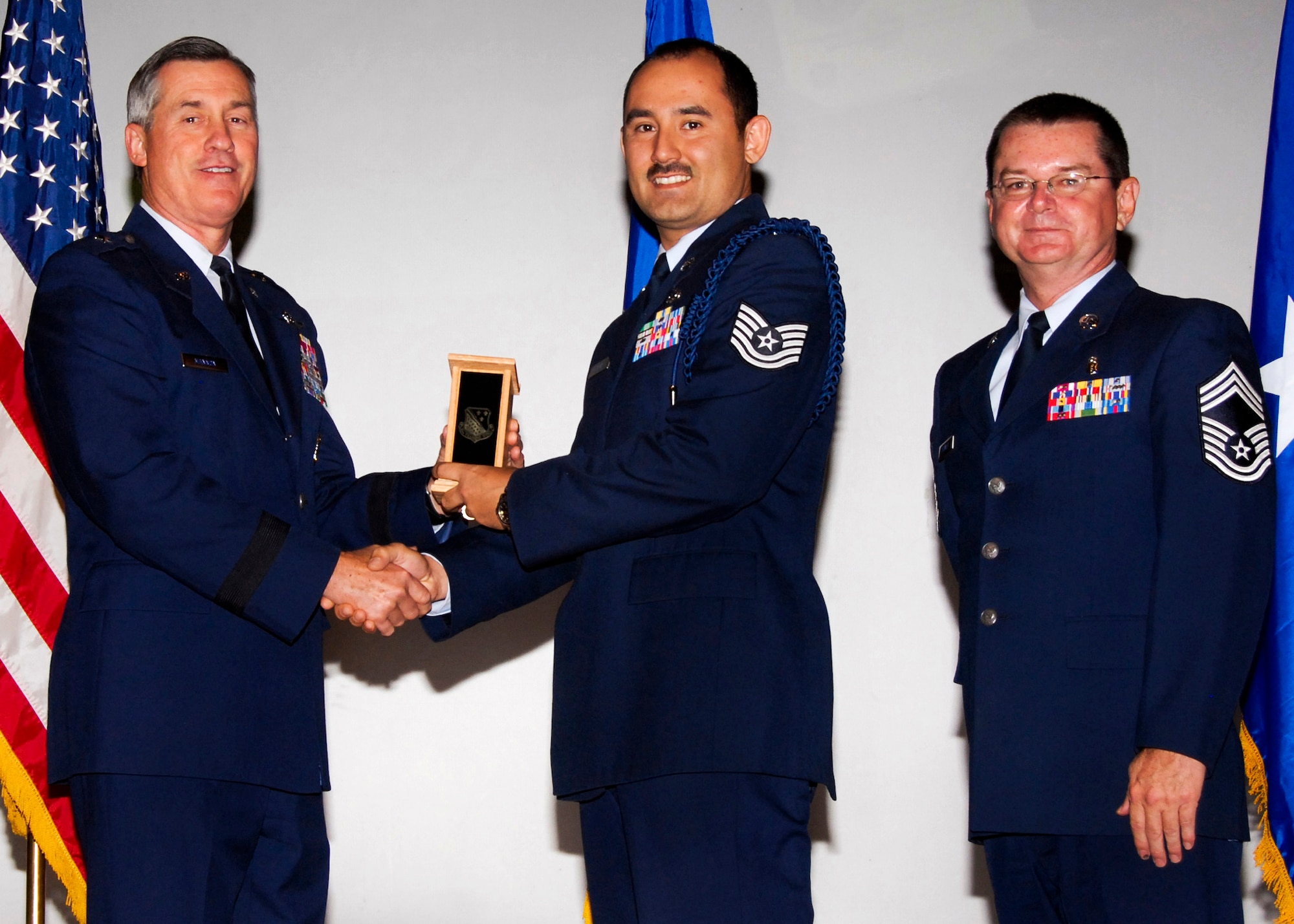 Tech. Sgt. Wesley Garcia, center, of the 82nd Training Group accepts the Junior Military Training Leader of the Quarter award from Brig. Gen. O.G. Mannon, 82nd Training Wing commander, Nov. 20 during the Quarterly Tech Training Awards in the base theater. Also pictured is Chief Master Sgt. Michael Crowley, right, superintendent of the 882nd TRG. (U.S. Air Force photo/Harry Tonemah)