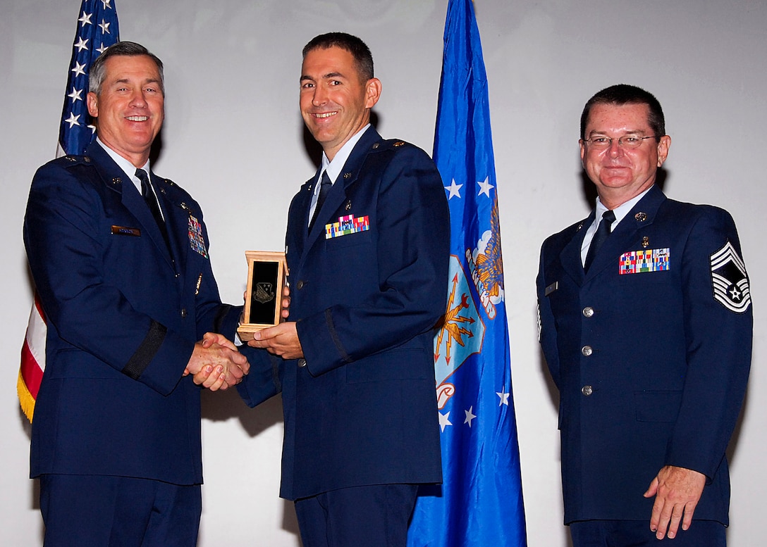 Maj. Darren Rhoton, center, of the 882nd Training Group accepts the Officer Instructor of the Quarter award from Brig. Gen. O.G. Mannon, 82nd Training Wing commander, Nov. 20 during the Quarterly Tech Training Awards in the base theater. Also pictured is Chief Master Sgt. Michael Crowley, right, superintendent of the 882nd TRG. (U.S. Air Force photo/Harry Tonemah)