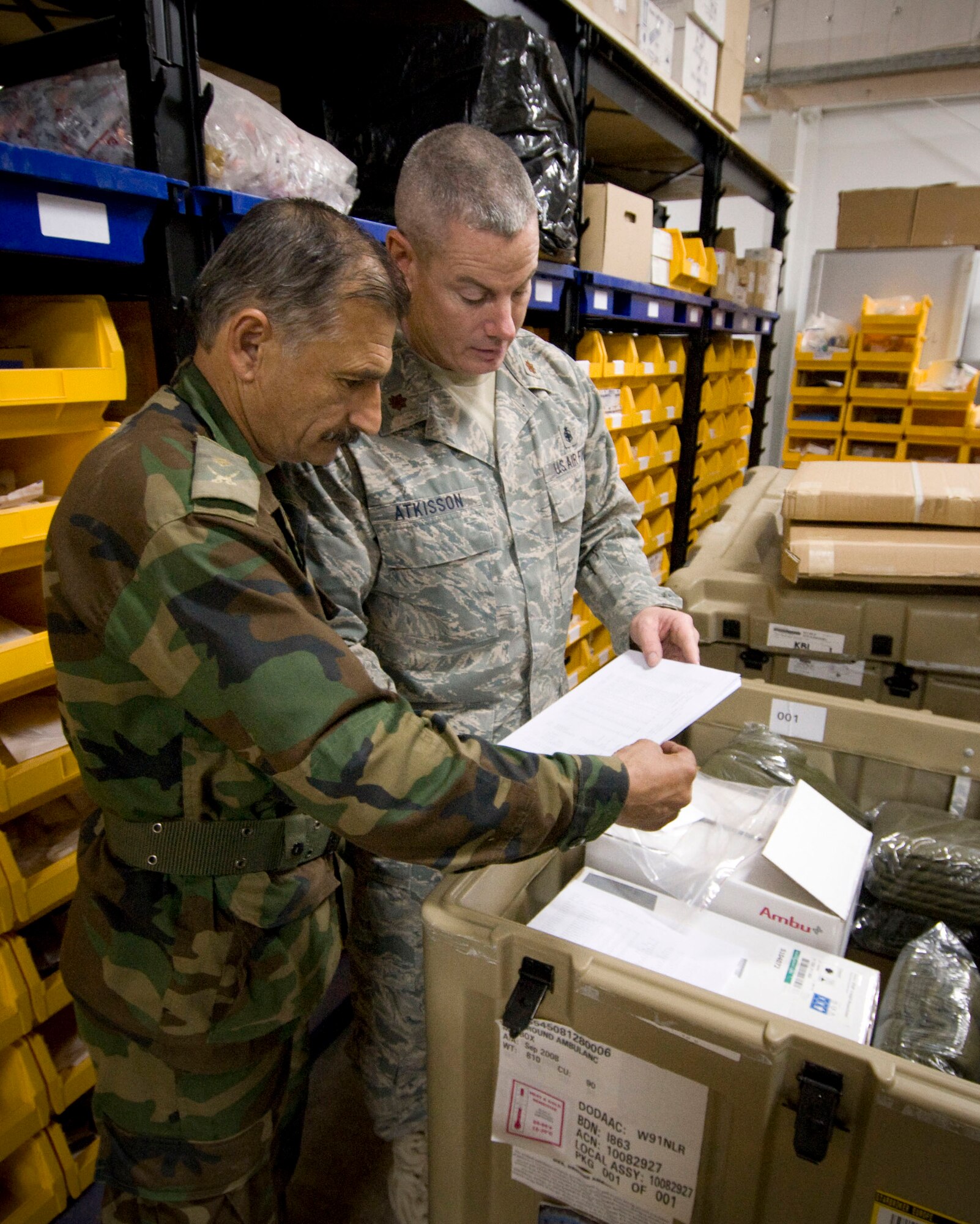 Maj. Jeff Atkisson, a medical logistics mentor for 205th Afghan Regional Security Integration Command embedded training team, reviews inventory with Maj. Gafar, an Afghan National Army office, in the warehouse at the Kandahar Regional Military Hospital on Camp Hero, Oct. 27, 2008. In addition to mentoring the ANA in the quality of healthcare, mentors are working to improve the medical supply chain in the country. (U.S. Air Force photo by Staff Sgt. Samuel Morse/Released)