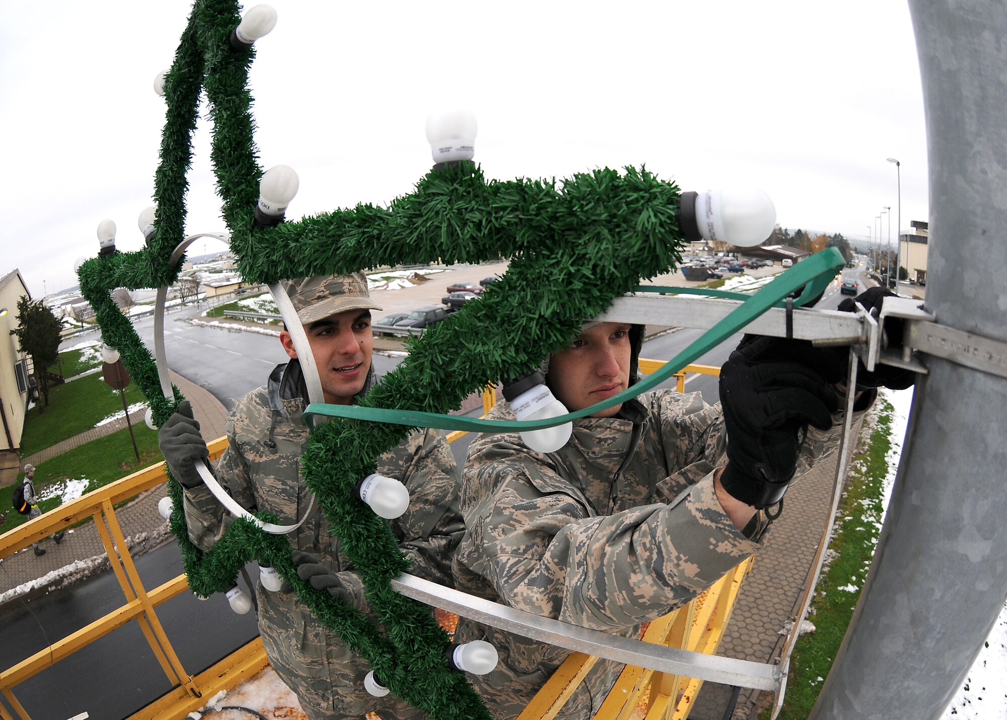 SPANGDAHLEM AIR BASE, Germany -- Airmen 1st Class Mahyar Rostami and Christopher Tripp, 52nd Civil Engineer Squadron, install Christmas decorations along the main road on base Nov. 24, 2008. (U.S. Air Force photo by Airman 1st Class Nathanael Callon)