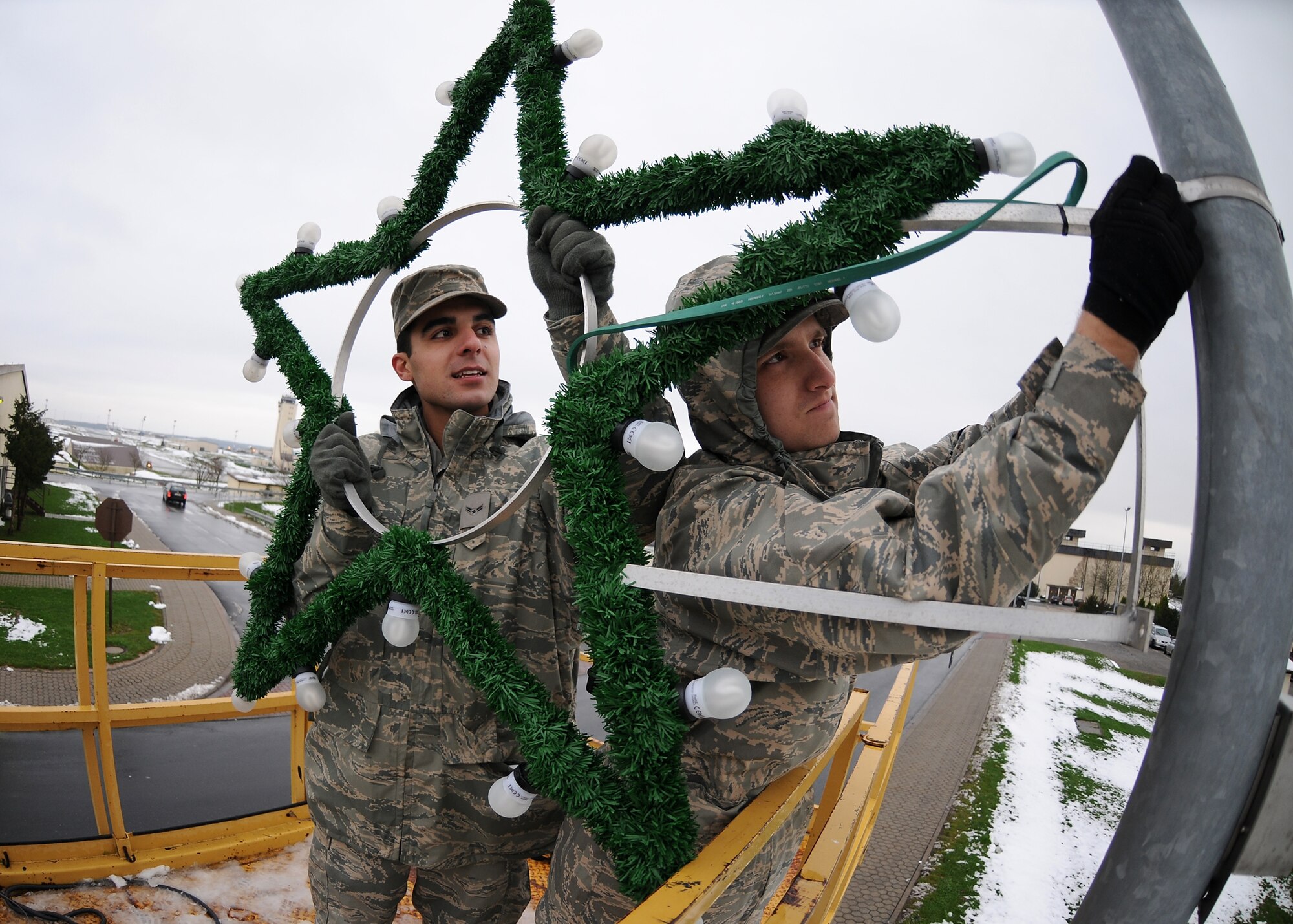 SPANGDAHLEM AIR BASE, Germany -- Airmen 1st Class Mahyar Rostami and Christopher Tripp, 52nd Civil Engineer Squadron, install Christmas decorations along the main road on base Nov. 24, 2008. (U.S. Air Force photo by Airman 1st Class Nathanael Callon)