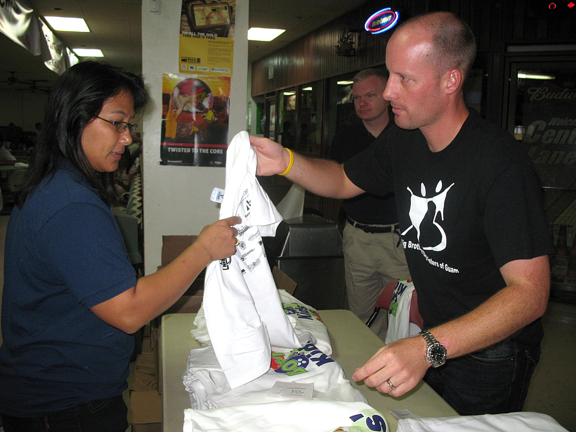 ANDERSEN AIR FORCE BASE, Guam -- Maj. Jeffrey Holt, 36th Logistics Readiness Squadron commander, hands an event t-shirt to local and event participant Rose SanNicholas at the Big Brothers and Big Sisters of Guam's 'Bowl for kids' sake' fundaraiser Nov. 22. (U.S. Air Force photo by Airman 1st Class Carissa Wolff)
