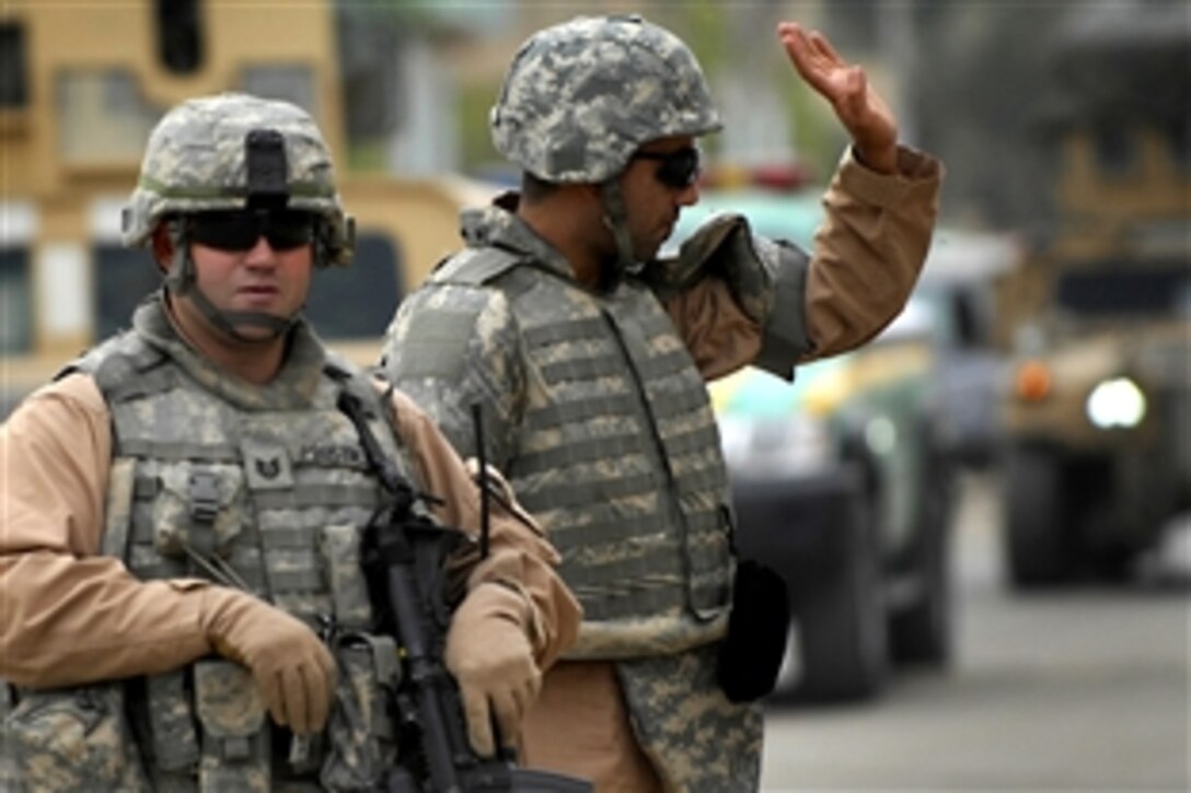 U.S. Air Force Tech. Sgt. Daniel Prosymchak and an interpreter wave at Iraqi civilians during a patrol in the Doura district of Baghdad, Iraq, Nov. 22, 2008. Prosymchak is assigned to Detachment 3, 732nd Expeditionary Security Forces Squadron, attached to the 1st Brigade Combat Team, 4th Infantry Division.