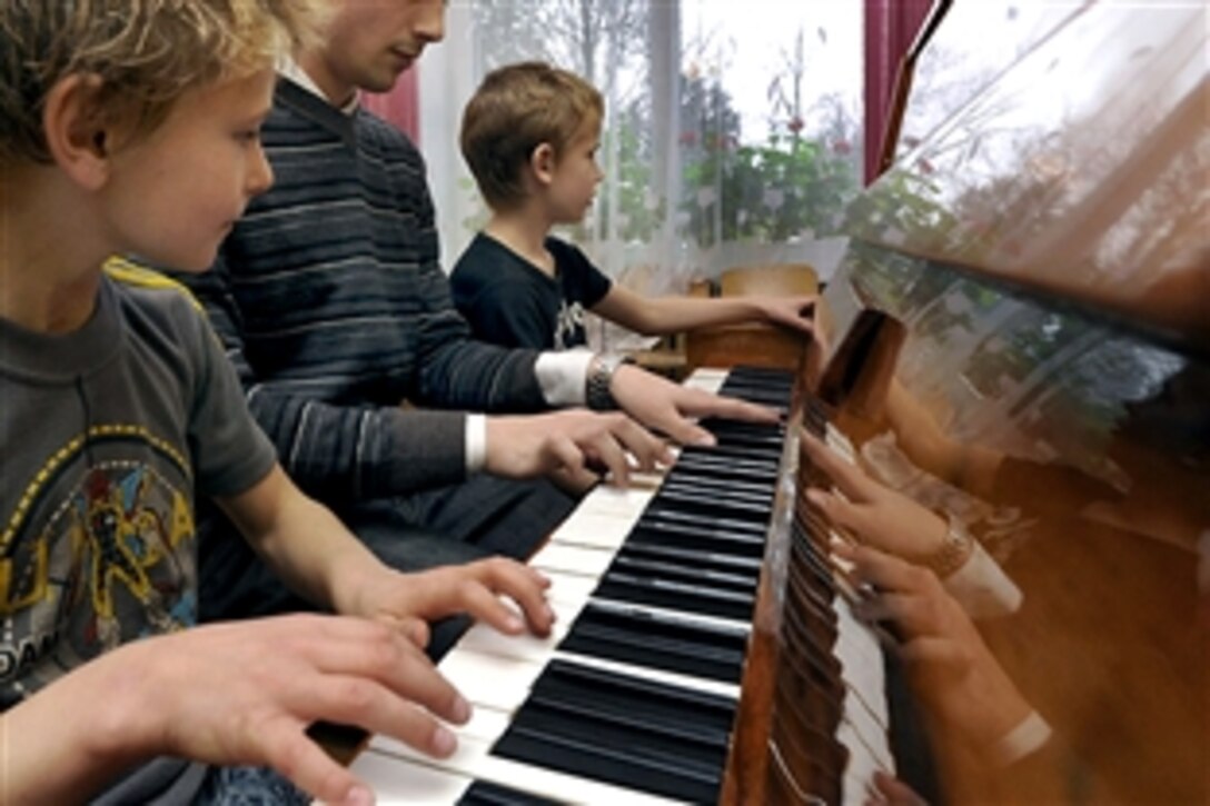 U.S. Air Force Airman 1st Class Kirk Rodgers, center, shares his musical talent with two children from a children's home in Vijurkai, Lithuania, Nov. 15, 2008. More than 20 U.S.airmen assigned to Royal Air Force Lakenheath, England, spent time with the children. Rodgers is a 493rd Expeditionary Fighter Squadron network operations technician. 