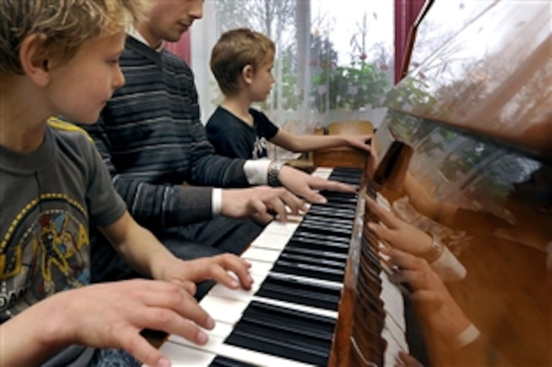 U.S. Air Force Airman 1st Class Kirk Rodgers, center, shares his musical talent with two children from a children's home in Vijurkai, Lithuania, Nov. 15, 2008. More than 20 U.S.airmen assigned to Royal Air Force Lakenheath, England, spent time with the children. Rodgers is a 493rd Expeditionary Fighter Squadron network operations technician. 