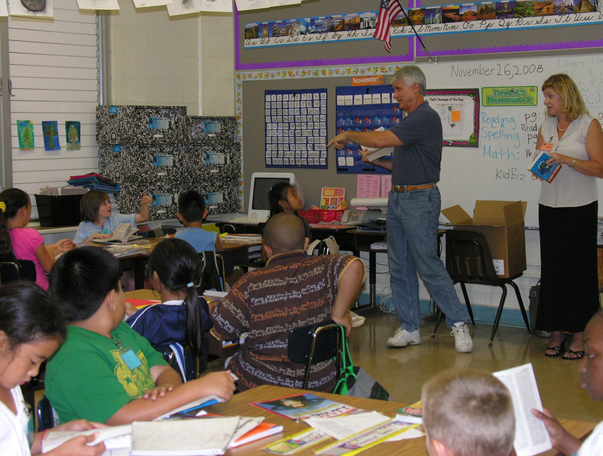 From left, Jeff Deer, a member of Rotary Club of Pearl Harbor and Susie Tuck, wife of Colonel Giovanni Tuck, 15th Airlift Wing Commander in explaining the contents of the dictionaries to students at Nimitz Elementary School on Nov 25.  (U.S. Air Force photo by Jackie Hites)