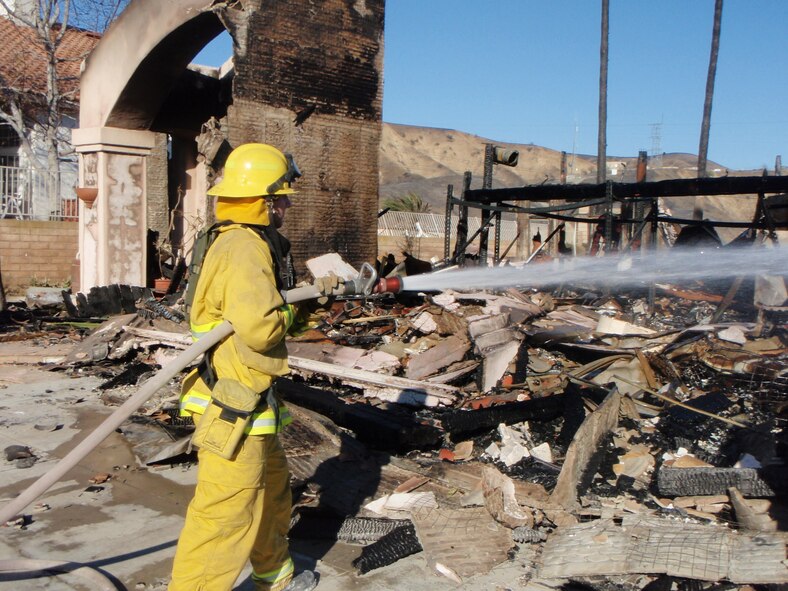 Firefighter Eric Russell hoses down rubble Nov. 16, 2008, at a home that was destroyed in Anaheim Hills, Calif. Mr. Russell was part of a four-person team from March Air Reserve Base (Calif.) Fire Department that supported Strike Team 6050A in Riverside County, Calif. (Courtesy photo)