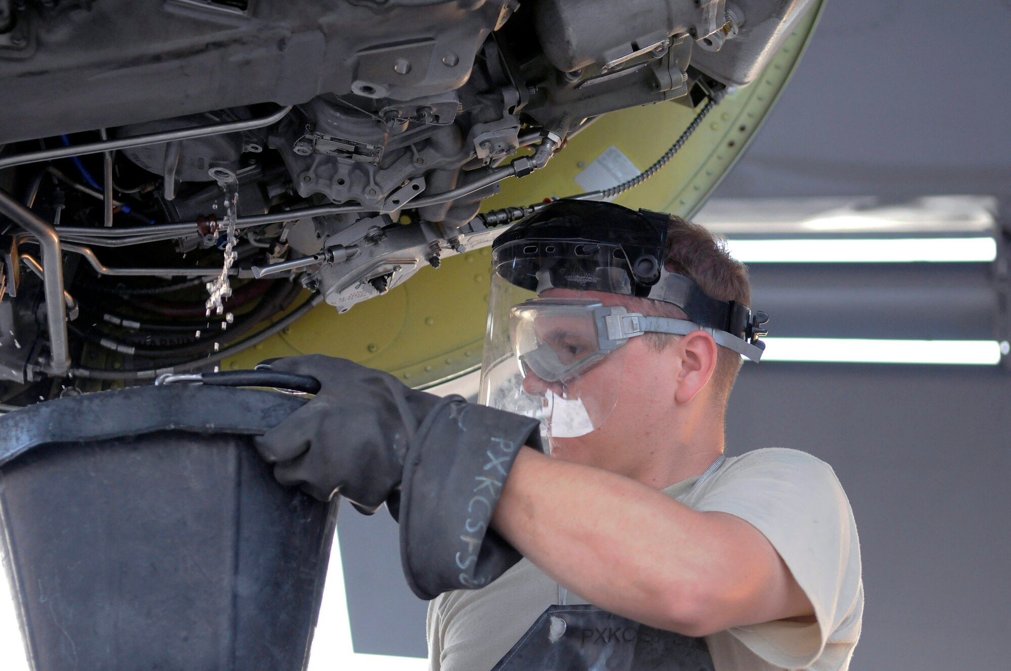 Staff Sgt. Anthony Hernandez holds a bucket catching extra fuel after removing the fuel filter during a 120-hour inspection on a KC-135 Stratotanker engine Nov. 20 at an air base in Southwest Asia. KC-135s provide the core aerial refueling capability for the Air Force and support to Navy, Marine Corps and allied nation aircraft in the U.S. Central Command area of responsibility. Sergeant Hernandez is a native of Barstow, Calif., and is deployed from McConnell Air Force Base, Kan. He is assigned to the 379th Expeditionary Aircraft Maintenance Squadron. (U.S. Air Force photo/Tech. Sgt. Michael Boquette) 
