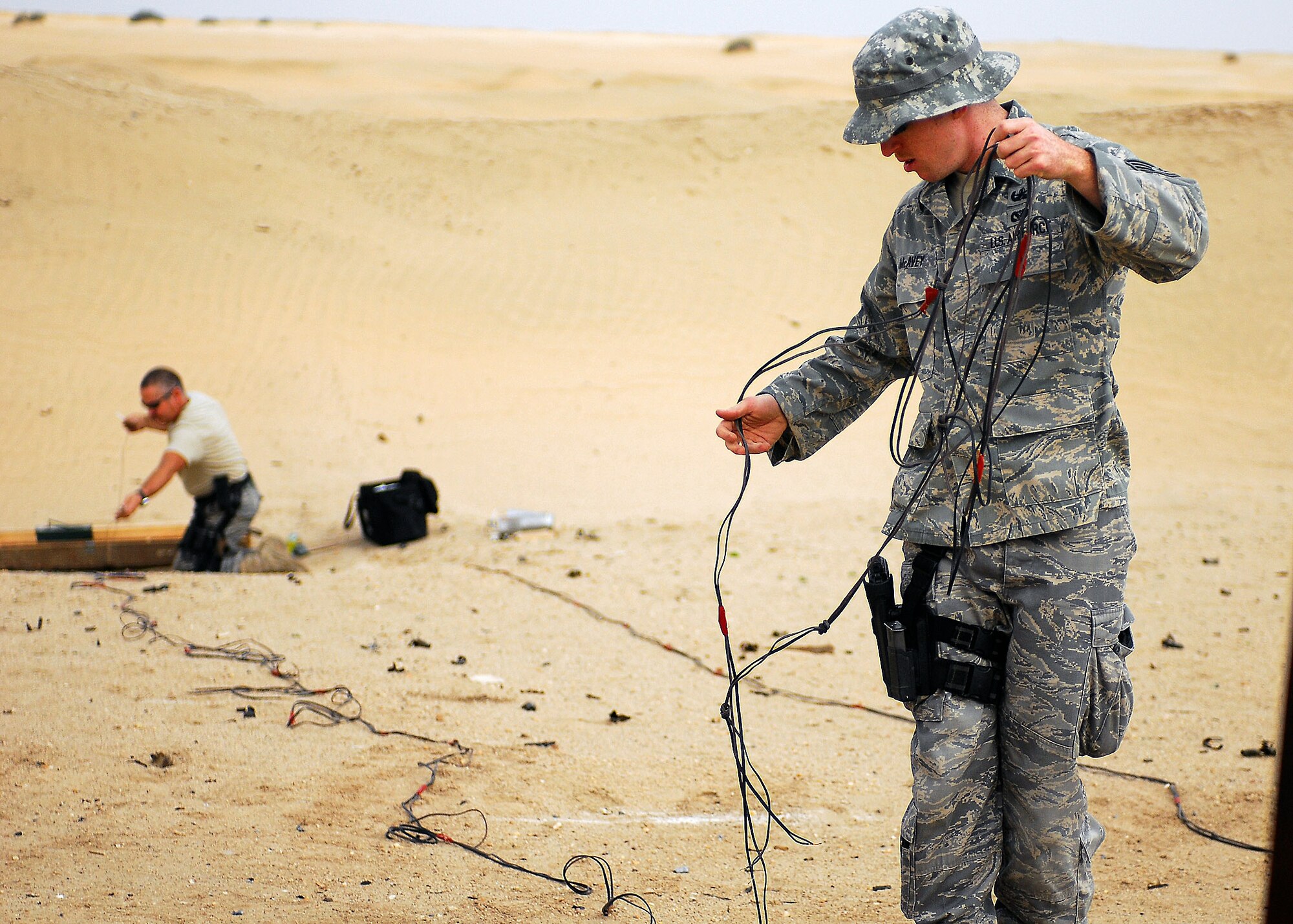 Staff Sgt. David Barrett (rear) and Staff Sgt. Brenden McAvey, 386th Expeditionary Civil Engineering Explosive Ordnance Disposal Flight members, work to set up a detonation site outside the wire at an air base in Southwest Asia. Airmen in the 386th EOD flight have safely cleared almost 1,000 unexploded ordinance devices during their six-month deployment here. (U.S. Air Force photo/Capt. Suzanne VanderWeyst)