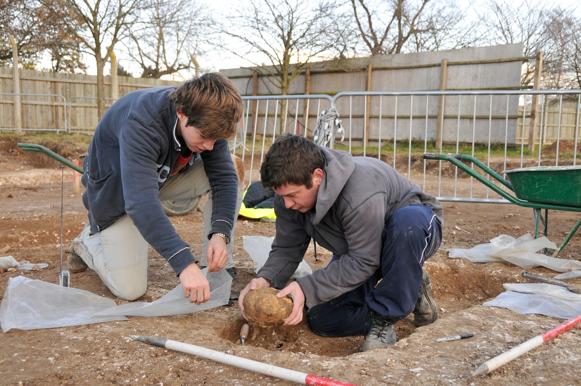 Edman Frieser, a junior site assistant with the Suffolk County Council Archaeological Service, hold open a plastic bag, while John Sims, an archaeologist with the service, carefully moves the skull into a bag Nov 24 at RAF Lakenheath, England. The skull and other skeletal remains will later be studied. (U.S. Air Force photo by Airman 1st Class Perry Aston)