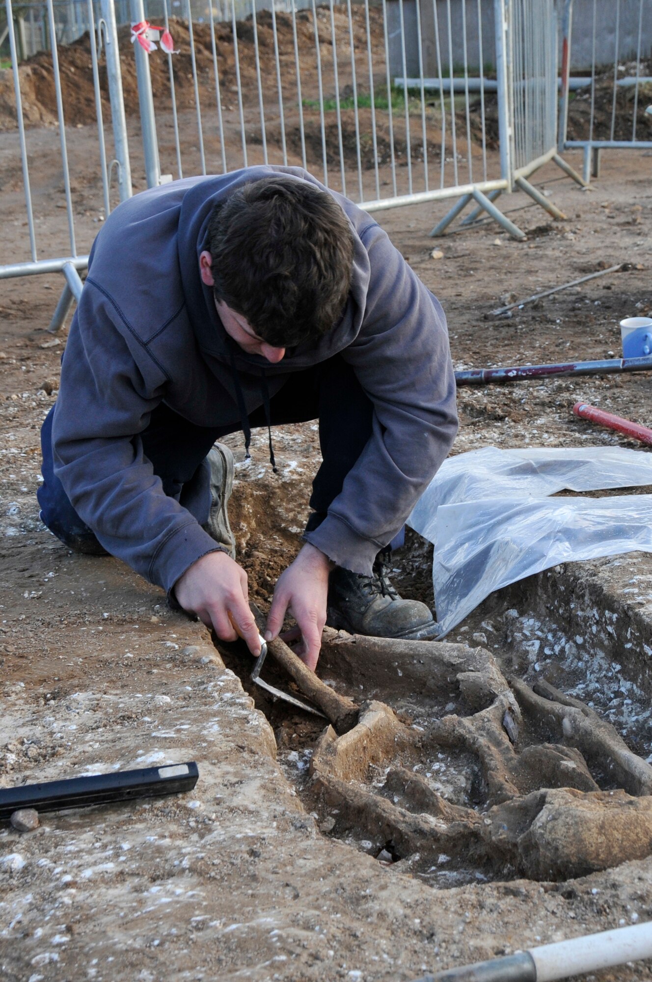 John Sims, an archaeologist with the Suffolk County Council Archaeological Service, carefully removes a femur from a skeleton to be placed in a bag Nov 24 at RAF Lakenheath, England. Out of the five bodies found two have so far been removed to be further studied. (U.S. Air Force photo by Airman 1st Class Perry Aston)