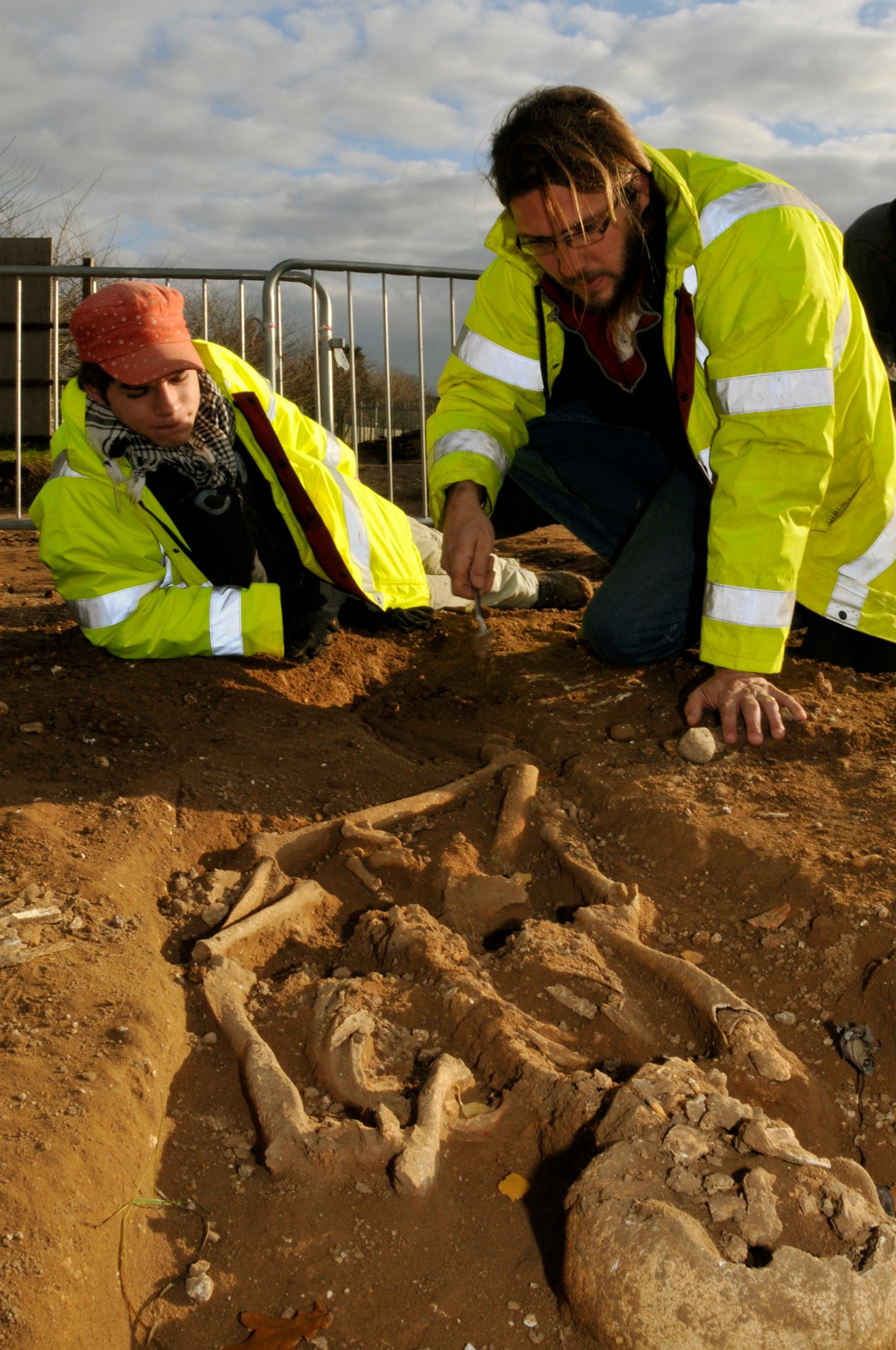 John Craven, gives Edman Frieser, both from the Suffolk County Council Archaeological Service, a few pointers on removing the sediment away from the remains of 2,000 year old skeleton Nov 24 at RAF Lakenheath, England. The archaeologist tries their best to keep the bones intact since the skull has already been destroyed by farming equipment. (U.S. Air Force photo by Airman 1st Class Perry Aston) 