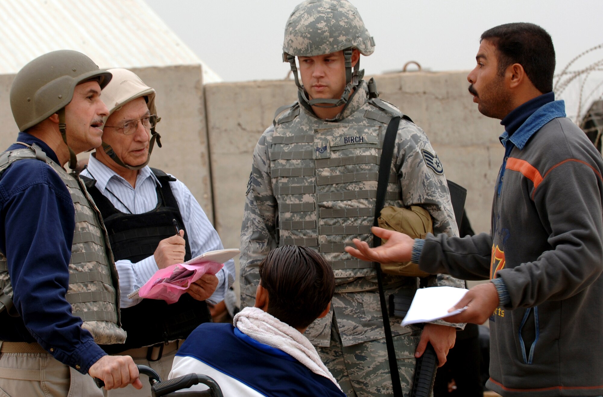 Staff Sgt. Trevor Birch works with local Iraqis and cultural advisors outside an entry control point before running patients to the Air Force Theater Hospital for treatment at Joint Base Balad, Iraq, Nov. 20. U.S. servicemembers contracted a project, which included a new waiting room and security fence upgrade, at the ECP to enhance relations with the Iraqis who visit here to work, conduct business or seek medical assistance. Birch, of the 332nd Expeditionary Medical Group Host Nation Patient Liaison Office, is deployed from Lackland Air Force Base, Texas. He is a native of Midland, Mich. (U.S. Air Force photo/Tech. Sgt. Erik Gudmundson)