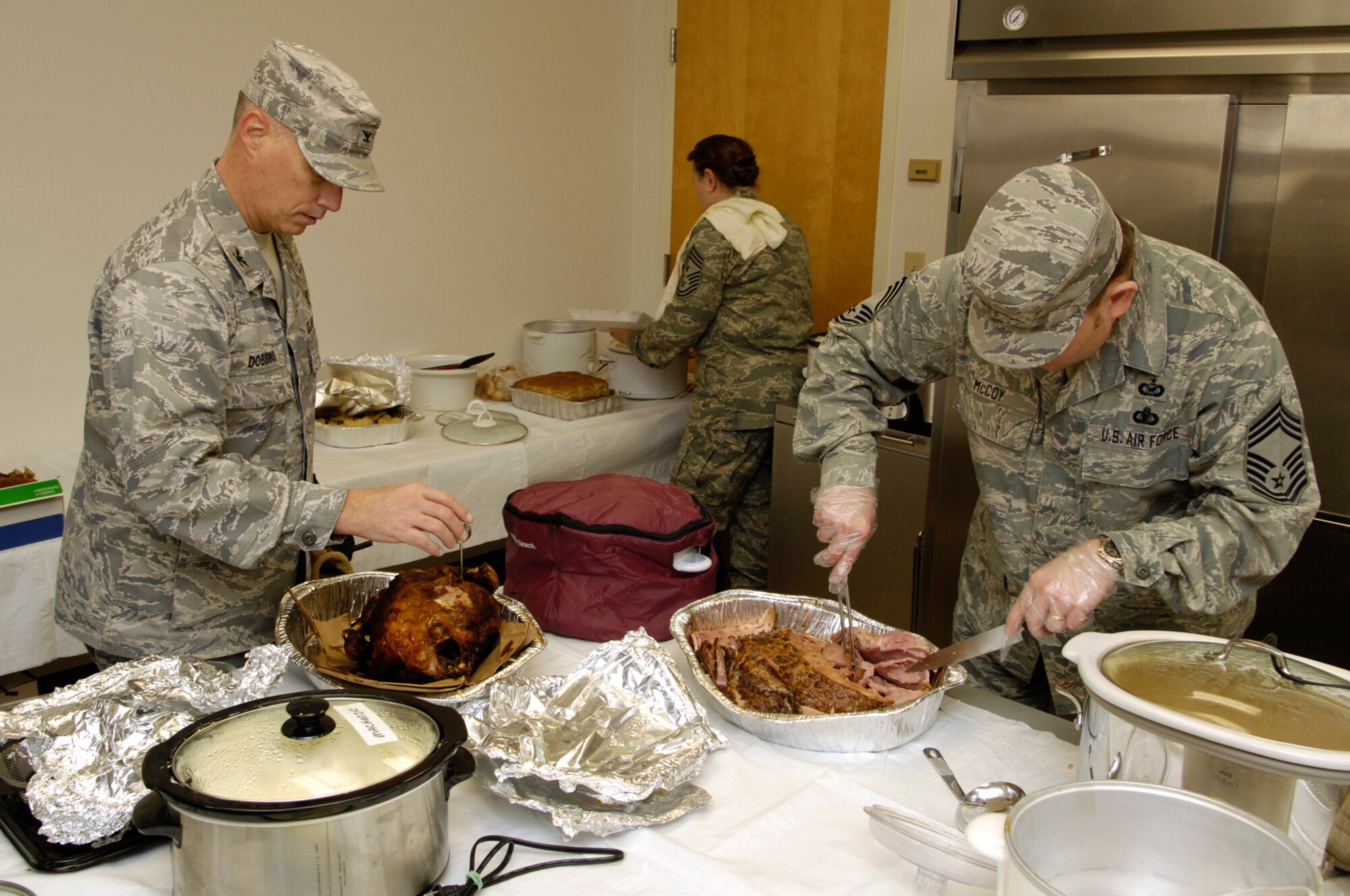 Col. Randy Dobbins, 66th Medical Group commander, Chief Master Sgt. Karen McCoy, 66th Air Base Wing and Electronic Systems Center command chief (center), and Chief Master Sgt. Michael McCoy, 66th Mission Support Group superintendent, prepare to serve lunch to 66 ABW personnel.  (U.S. Air Force photo by Mark Wyatt)