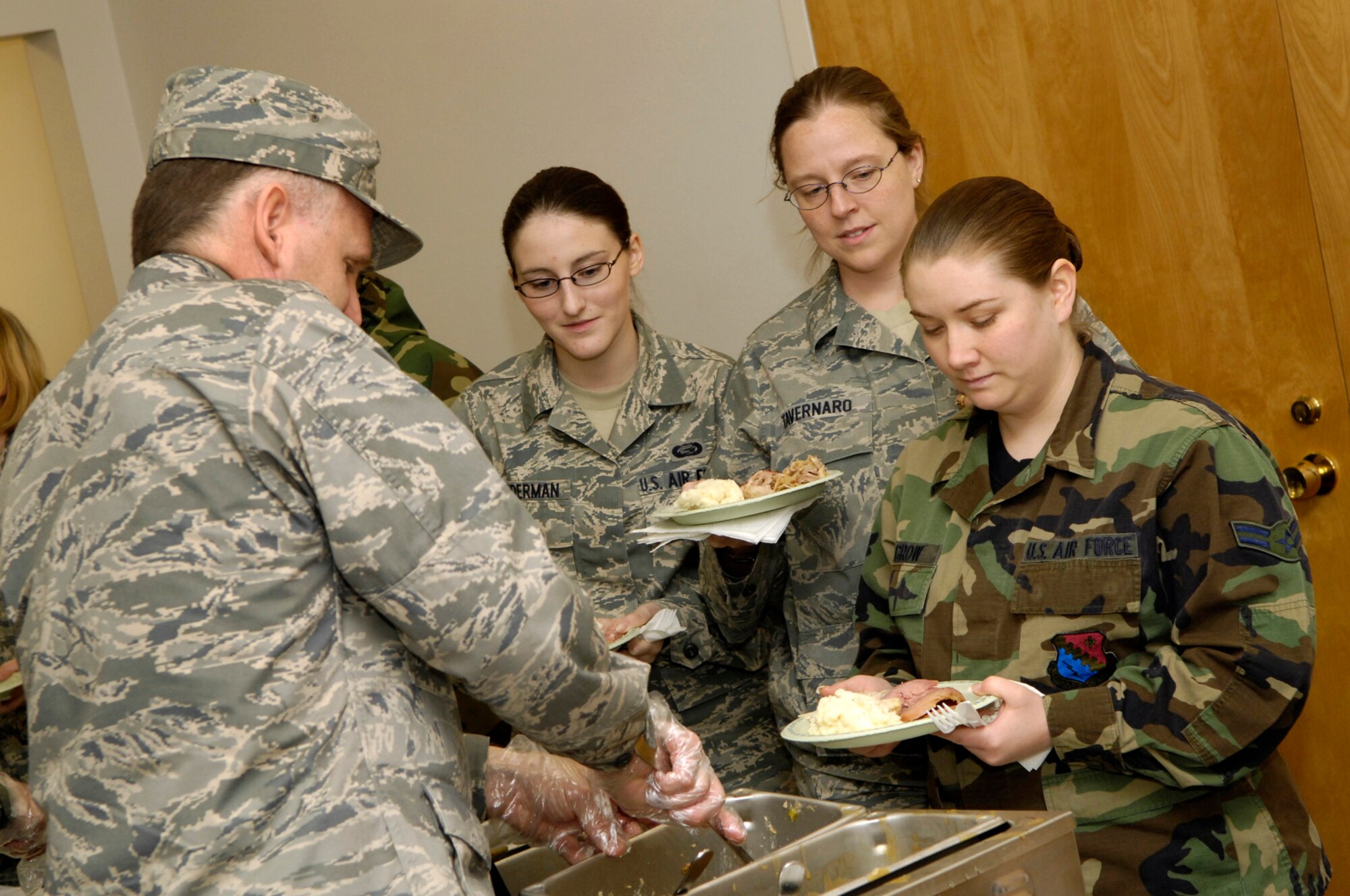 Lt. Col. Gerald Parish, 66th Mission Support Group vice commander, serves Airman 1st Class Brittni Linderman, Senior Airman Lana Tavernaro and Airman 1st Class Jamie LaGrow at the 66th Air Base Wing Wingman Day lunch, held Nov. 21 at the Hanscom Conference Center.  Wingman Day activities were held base-wide to celebrate camaraderie and encourage team building among Hanscom personnel.  (U.S. Air Force photo by Mark Wyatt)