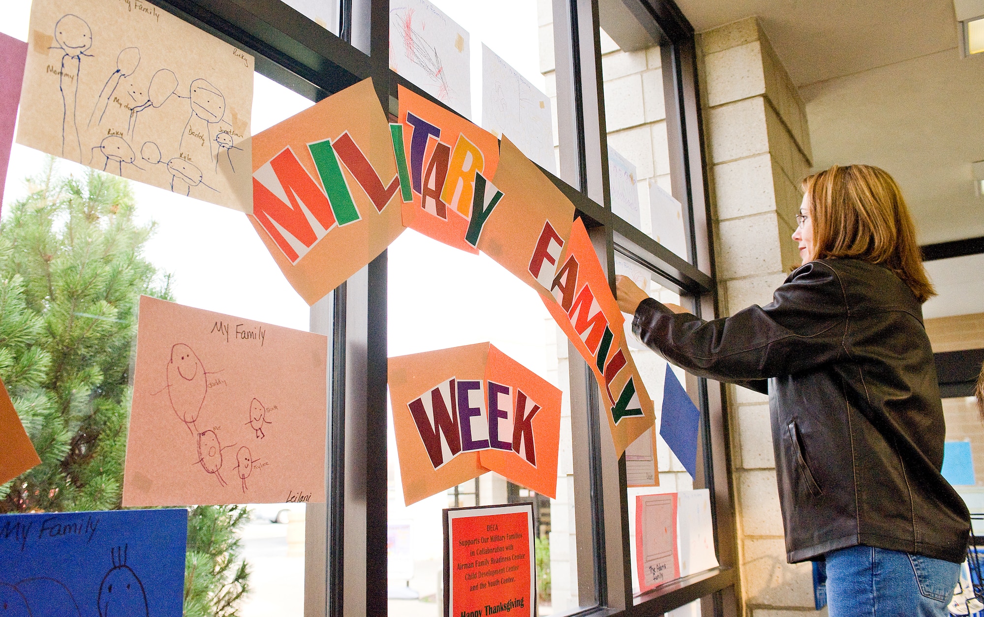Laura Chupp, 436th Mission Support Squadron Airman and Family Readiness Center Community Readiness Consultant, hangs artwork in the Commissary Nov. 24 for Military Family Appreciation Week. The preschool classes at the Child Development Center drew pictures of their family, which will hang in the Commissary through Nov. 28. (U.S. Air Force Photo/Tom Randle)