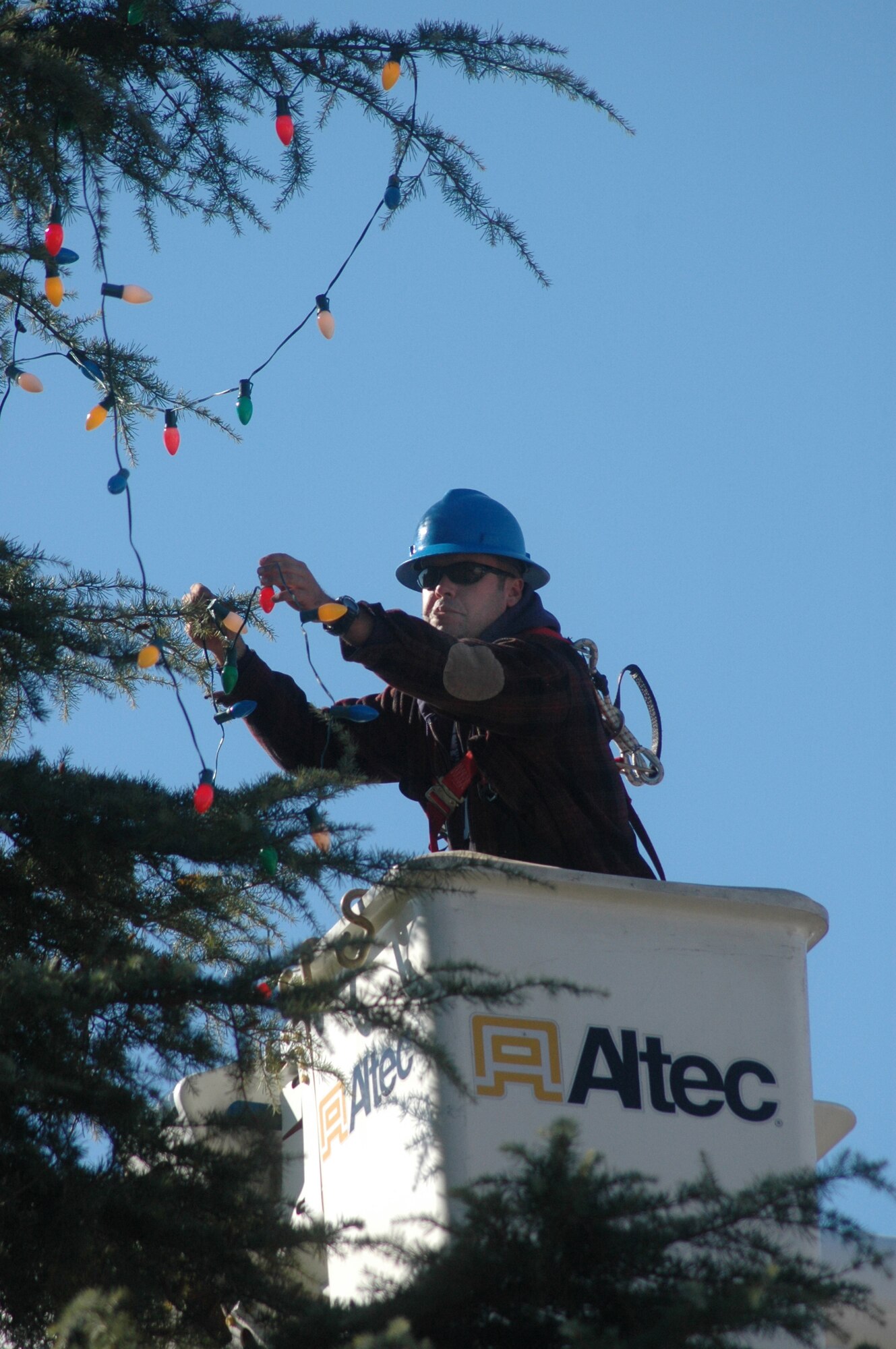 Bill Bandy, 78th CES exterior electric shop, puts one of forty strings of Christmas lights on the Robins Chapel tree from a bucket truck Nov. 20. U. S. Air Force photo by Sue Sapp