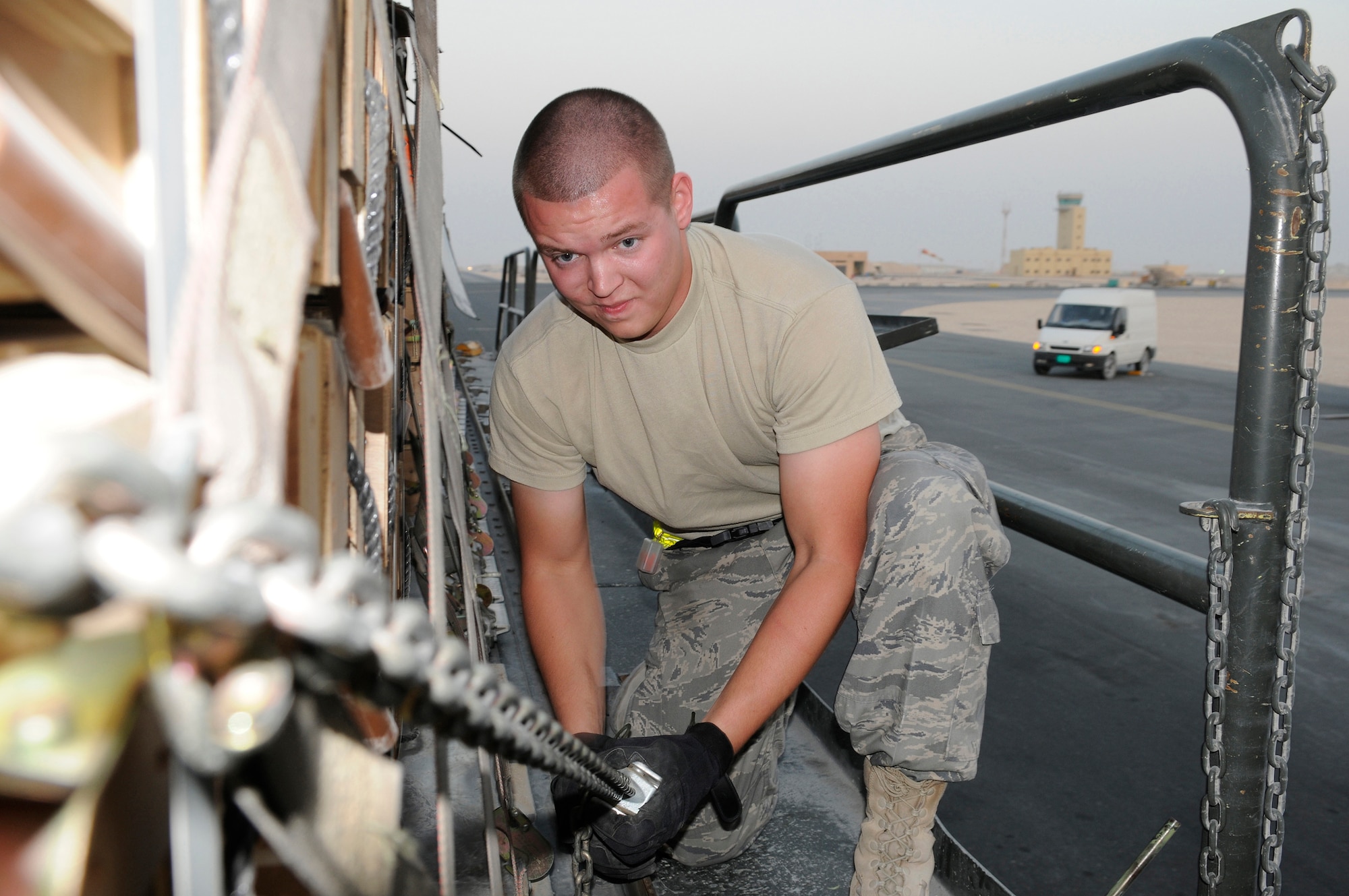 Airman 1st Class Brian Foxworth, an air transportation journeyman assigned to the 8th Expeditionary Air Mobility Squadron, tightens a chain holding a pallet in place on a 60K loader, Nov. 25, 2008, at an undisclosed air base in Southwest Asia.  The chains are used to keep the pallet loads from shifting during transit from the C-17 Globemaster III to the storage area.  Airman Foxworth is a native of Austin, Texas, and is deployed from McGuire Air Force Base, N.J. He is here supporting Operations Iraqi and Enduring Freedom and Joint task Force-Horn of Africa.  (U.S. Air Force photo by Tech. Sgt. Michael Boquette/Released)