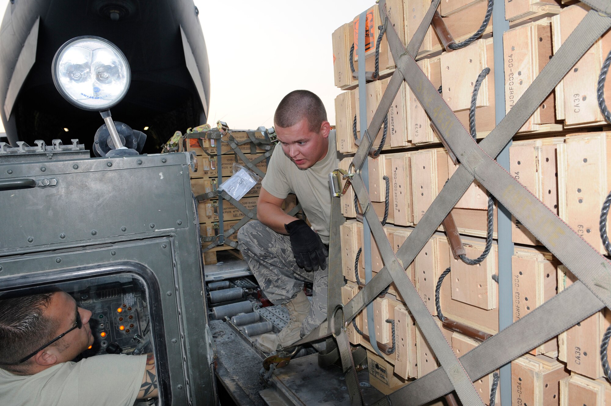 Airman 1st Class Brian Foxworth, an air transportation journeyman assigned to the 8th Expeditionary Air Mobility Squadron, double checks tie down points as Senior Airman Dane Childers, an air transportation journeyman assigned to 8 EAMS, operates the 60K loader, Nov. 25, 2008, at an undisclosed air base in Southwest Asia.  The chains are used to keep the pallet loads from shifting during transit from the C-17 Globemaster III to the storage area.  Airman Childers hails from Waldorf, Md., and is deployed from Dover Air Force Base, Del. Airman Foxworth is a native of Austin, Texas, and is deployed from McGuire AFB, N.J.  Both are here supporting Operations Iraqi and Enduring Freedom and Joint task Force-Horn of Africa.  (U.S. Air Force photo by Tech. Sgt. Michael Boquette/Released)