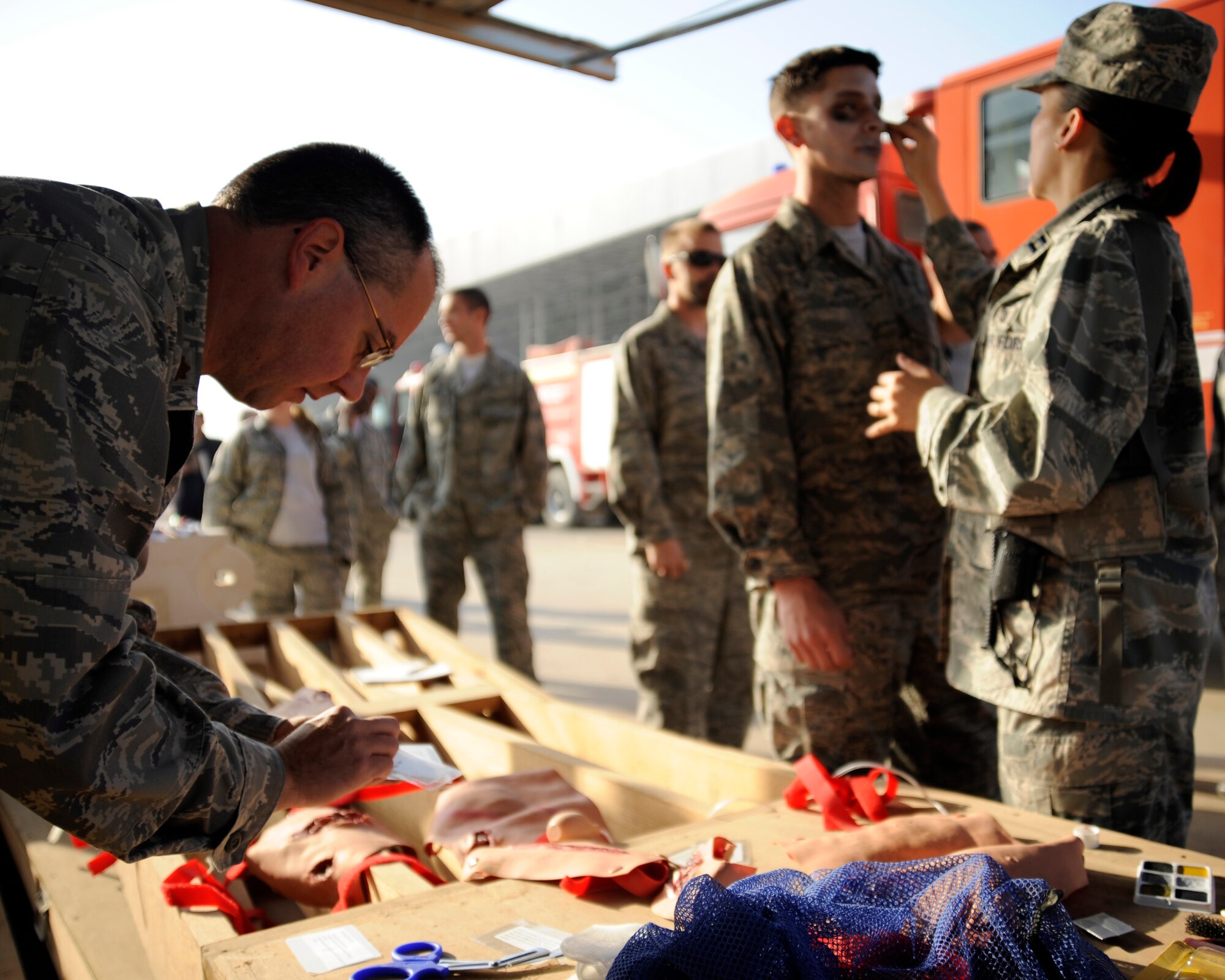 U.S. Air Force Major Christopher Hammond, chief nurse for the 447th Expeditionary Medical Squadron, sorts wounded cards while Capt. Sunny Holden, chief medical advisor for the 321st Air Expeditionary Advisory Squadron, applies moulage to mock accident casualty Senior Airman Jeremy Fazely, a ground radio technician with the 447th Air Expeditionary Communications Squadron, at New Al-Muthana Air Base, Iraq on Nov. 21, 2008. The preparation is for a major accident response exercise involving U.S. and Iraqi forces. (U.S. Air Force photo/Staff Sgt. Paul Villanueva II)