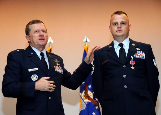 ANDERSEN AIR FORCE BASE, Guam - Brig. Gen. Phil Ruhlman, 36th Wing commander, honors Tech. Sgt. Michael Allen, 36th Contracting Squadron construction contracting officer, after presenting him with a Bronze Star Medal in a ceremony at the base theater here Nov 26.  Sergeant Allen, a 13-year Air Force veteran, was awarded the BSM for his service while deployed to Baghdad, Iraq, from Jan. 1 to June 28, 2008.  Contracts the sergeant was responsible for improved Iraqi Army response times for counter insurgency operations in Mosul, provided Iraqi commanders infrastructure and resources to hone unit combat skills and bolstered the Ministry of Defense’s self-sufficiency efforts, according to the citation.  The citation also recognized Sergeant Allen’s life-saving actions following a rocket attack where he directed rescue efforts and carried out wounded personnel for medical attention.   The BSM is awarded to Airmen who have distinguished themselves by heroic or meritorious achievement or service not involving participation in aerial flight, in connection with military operations against an armed enemy. (U.S. Air Force photo by Airman 1st Class Courtney Witt)