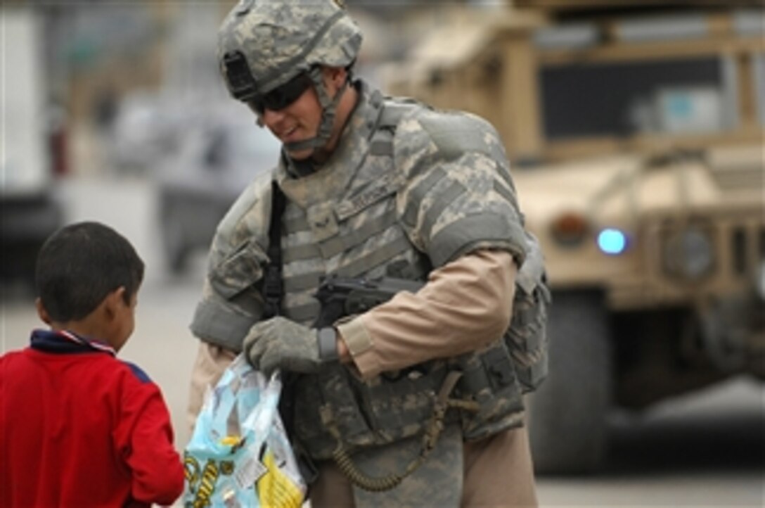 U.S. Air Force Airman 1st Class Justin Iverson, assigned to Detachment 3, 732nd Expeditionary Security Forces Squadron, attached to the 1st Brigade Combat Team, 4th Infantry Division, hands out candy to Iraqi children during a patrol in the Doura district of Baghdad, Iraq, on Nov. 22, 2008.  
