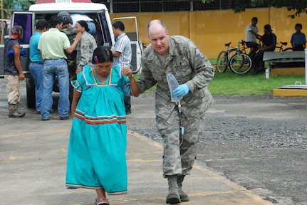 LAS TABLAS, PANAMA-- Master Sgt. James Eidson, a Joint Task Force-Bravo emergency medical technician, escorts a flood victim to a UH-60 Black Hawk helicopter Wednesday. The woman was unable to get to a hospital because the roads were flooded. The JTF-Bravo helicopter transported the woman and five other patients from a remote airfield to an airport where an ambulance met the patients and transported them to a local hospital. (U.S. Air Force photo by 1st Lt. Candace Park)