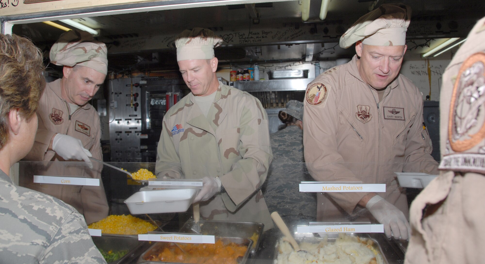 SOUTHWEST ASIA -- (Left to right) The 380th Air Expeditionary Wing Commander Brig. Gen. HD Polumbo, Jr., serves Thanksgiving Day vittles to base members with Lt. Col. Michael Shea, 380th Expeditionary Aircraft Maintenance Squadron commander, and Lt. Gen. Gary North, Air Forces Central and 9th Air Force commander, at Roy's Diner here Nov. 27. The 380th AEW is just one stop on General North's itinerary visiting deployed Airmen in the Area of Responsibility for the holiday. The AFCENT commander said Roy's is always one of his favorite stops in the AOR as the tented dining facility is reminscent of a "mom-and-pop restaurant back home in the states." This is the last Thanksgiving meal to be served at Roy's, as it is scheduled to be closed in the near future. The Containerized Deployment Kitchen is the last of its kind in the AOR. (USAF photo by Tech. Sgt. Denise Johnson) (released)