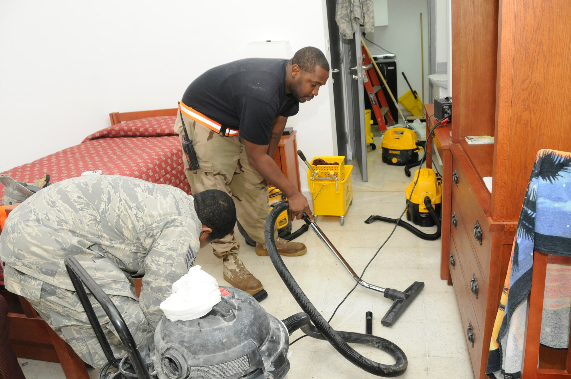 Staff Sgt. Grahame Evelyn uses a towel to dry the floor while Staff Sgt. Eric Green uses a wet vacuum to remove excess water from a flooded dorm room Nov. 26, at an undisclosed air base in Southwest Asia.  Both sergeants are heating, ventilation and air conditioning craftsmen assigned to the 379th Expeditionary Civil Engineer Squadron deployed in support of Operations Iraqi and Enduring Freedom and Joint Task Force-Horn of Africa. The flood was caused by a bad isolation valve and these 379 ECES members are responsible for minimizing water damage by removing all water from the area. Sergeant Evelyn, a native of Sumter, S.C., is deployed from Charleston Air Force Base, S.C., and Sergeant Green, a native of Saint Catherine, Jamaica, is deployed from Charleston AFB, S.C. (U.S. Air Force photo by Staff Sgt. Darnell T. Cannady/Released)