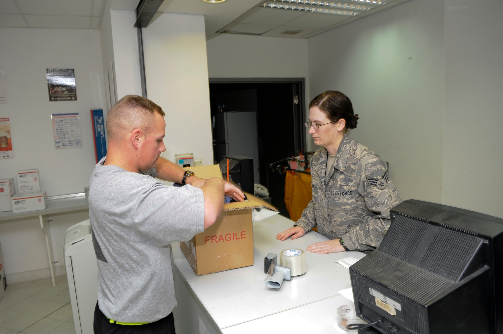 1st Lt. William Durband, 243 Air Defense Artillery, shows items he is mailing to Airman 1st Class Rebecca Goodwin, postal clerk assigned to the 379th Expeditionary Communications Squadron, Nov. 28, at an undisclosed air base in Southwest Asia.  The postal clerks are responsible for ensuring that a customs check is completed on all items being sent through the mail.  All packages are also x-rayed to ensure that no illegal or dangerous items are being mailed.  The postal center recommends packages sent by priority mail be sent out no later than 6 Dec., to allow time to clear customs and still make it to its destination by Christmas.  1st Lt. Durband, a native of Chicago Ill., is deployed from Fort Bliss, Texas.  Airman Goodwin hails from San Jose, Calif., and is deployed from Lajes Field, Azores, Portugal.  Both are deployed in support of Operations Iraqi and Enduring Freedom and Joint Task Force-Horn of Africa.  (U.S. Air Force photo by Tech. Sgt. Michael Boquette/Released)