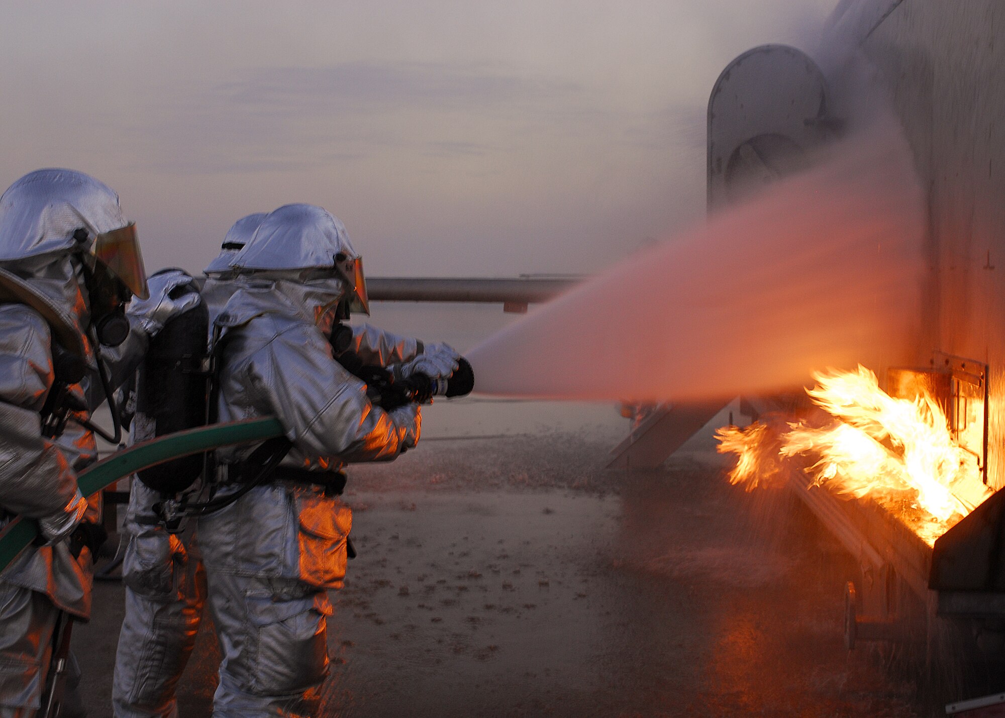 SOUTHWEST ASIA -- Firefighters from the 386th Expeditionary Civil Engineer Squadron, extinguish a fire on an aircraft fire trainer on Nov. 24 at a base in Southwest Asia. The firefighters must complete one daytime and nighttime live fire burn annually. (U.S. Air Force photo/Capt. Suzanne VanderWeyst)