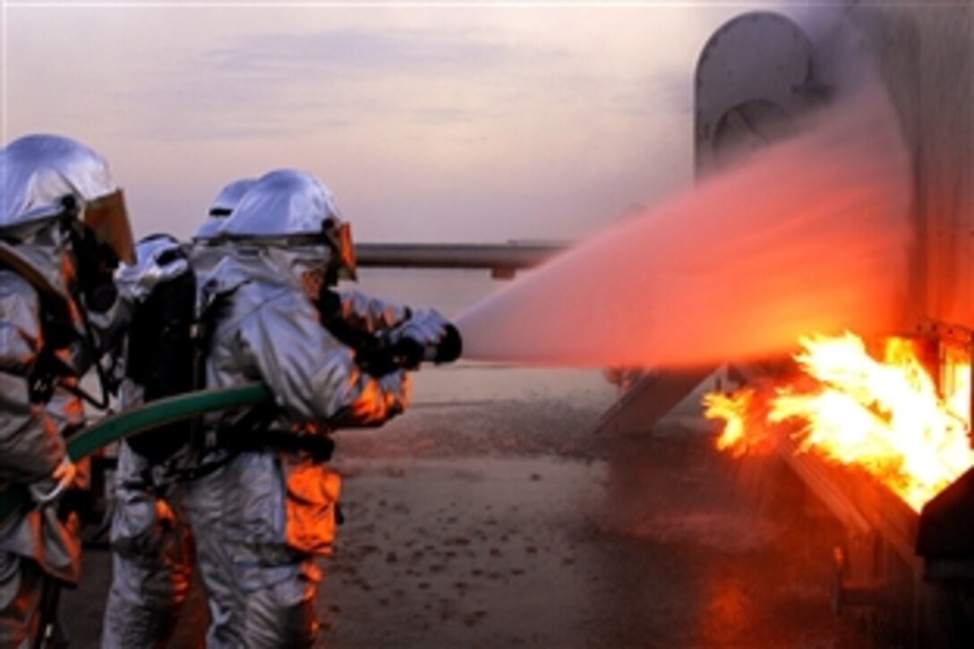 Firefighters assigned to the 386th Expeditionary Civil Engineer Squadron extinguish a fire on an aircraft fire trainer on a base in Southwest Asia, Nov. 24 , 2008. The firefighters must complete one daytime and nighttime live fire burn annually.